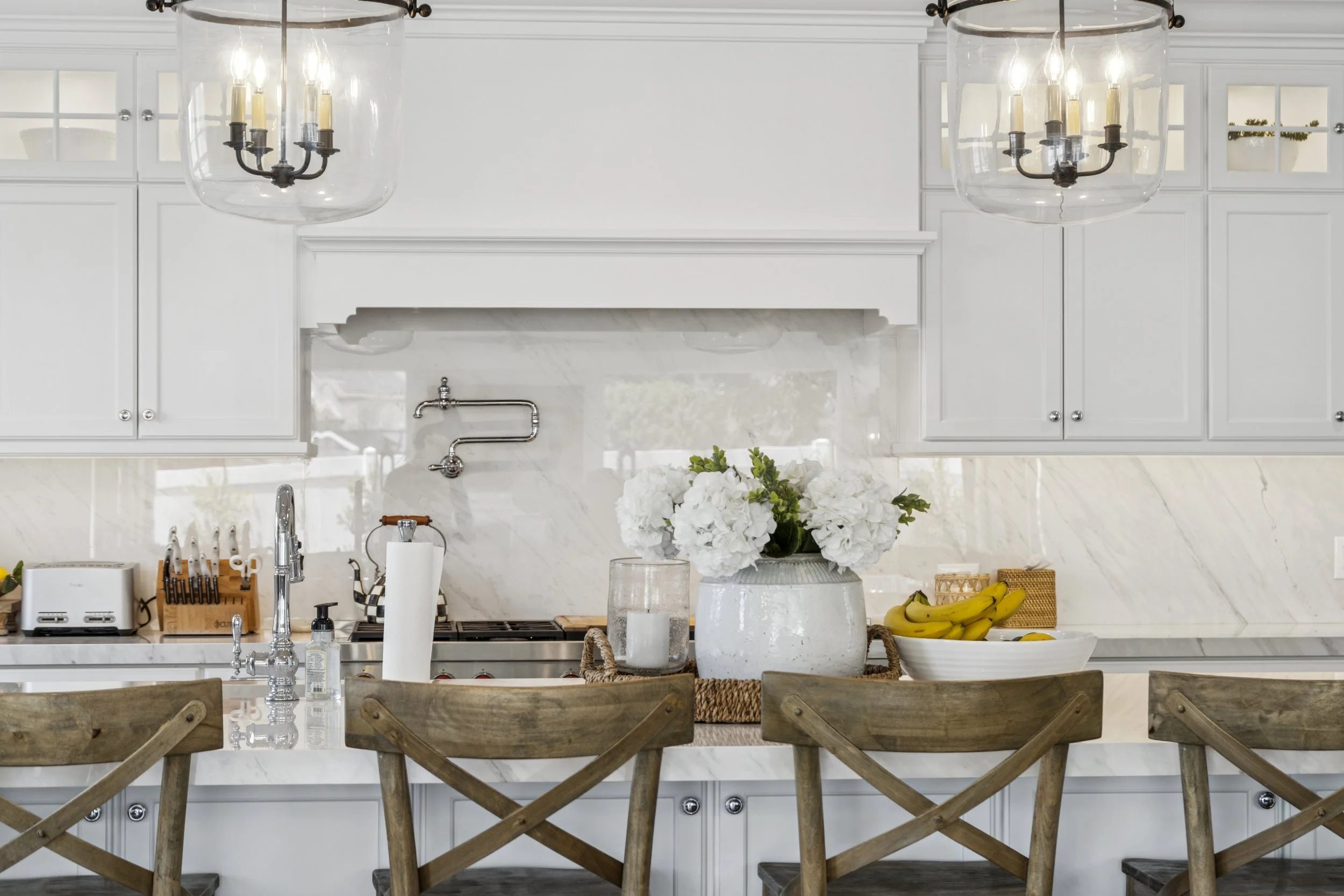 Open patio doors leading to a terrace with wicker furniture and a view of a house, against a colorful sunset sky.