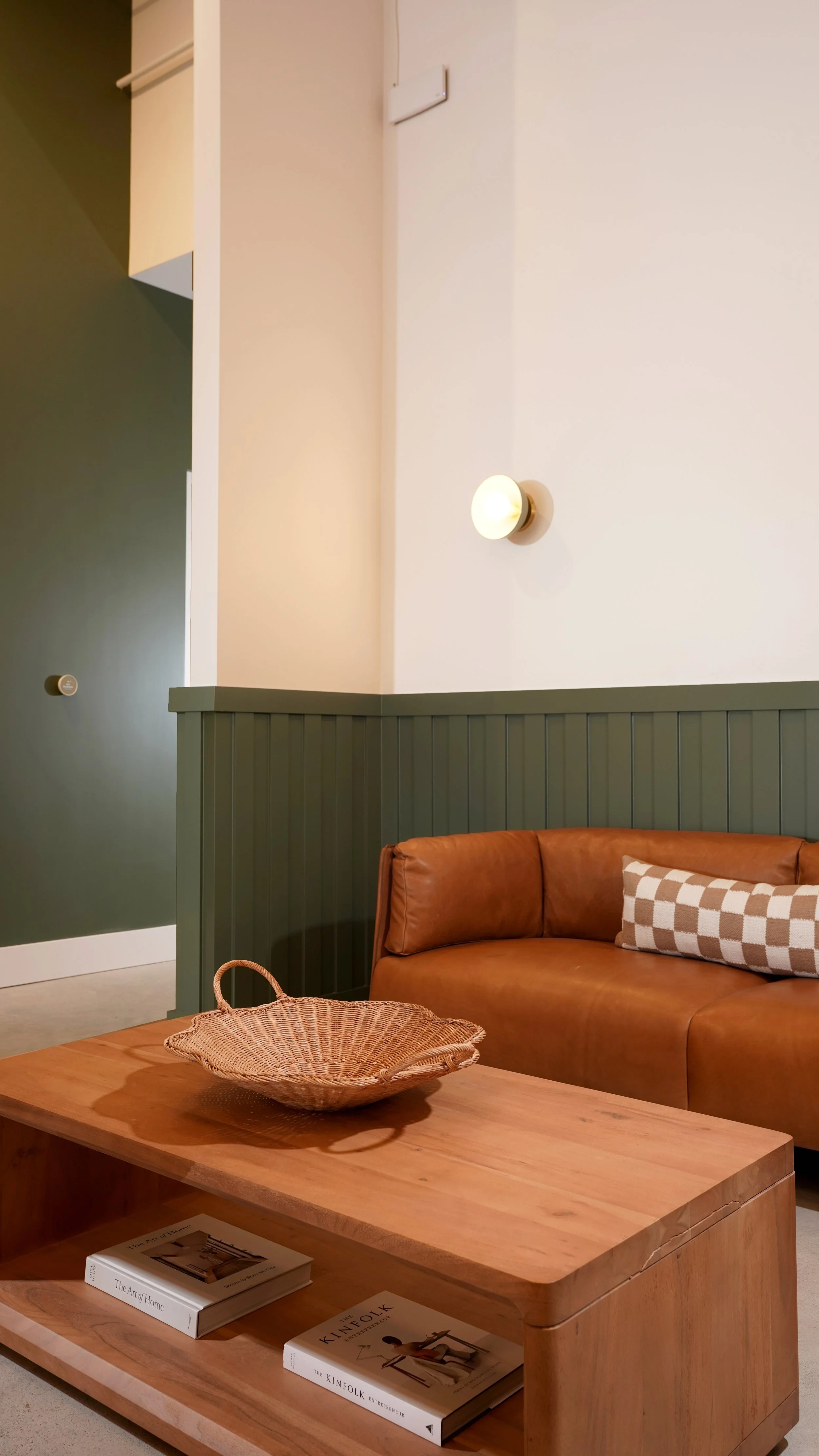 Close-up of coffee shop lounge seating with custom green wall paneling, wood furniture, and warm interior details in Laguna Hills, Orange County.