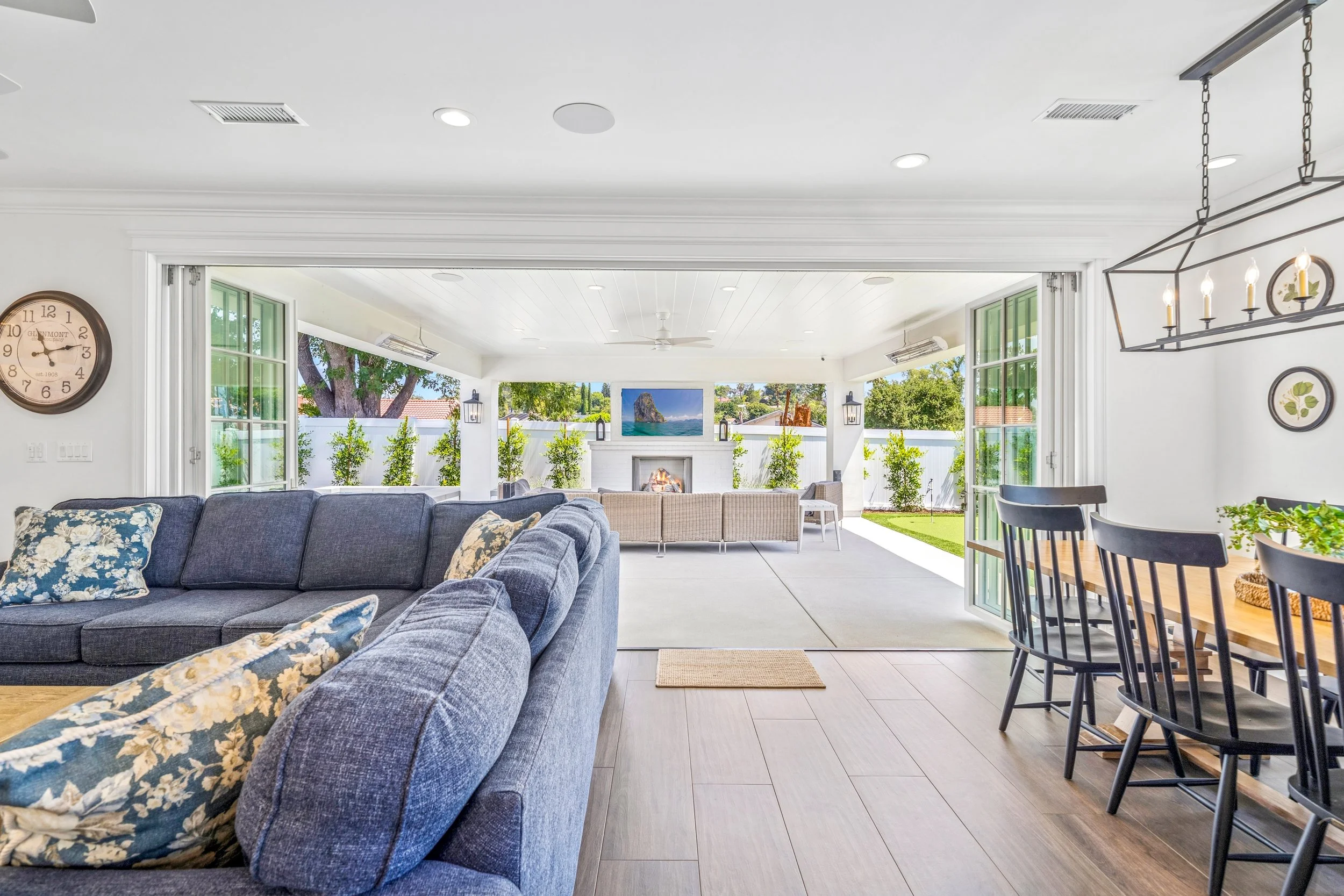 Open living and dining area with large folding glass doors connecting the Mission Viejo custom home to a covered outdoor patio and backyard entertaining space.