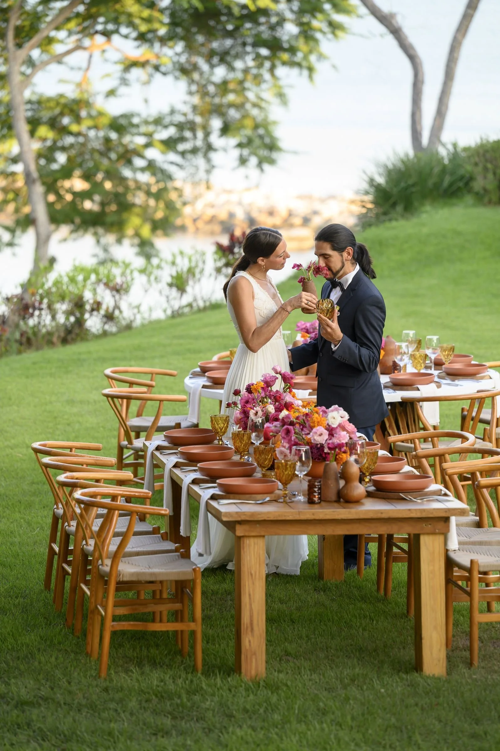 Bride and groom beside their long table in terracotta and magenta at sunset