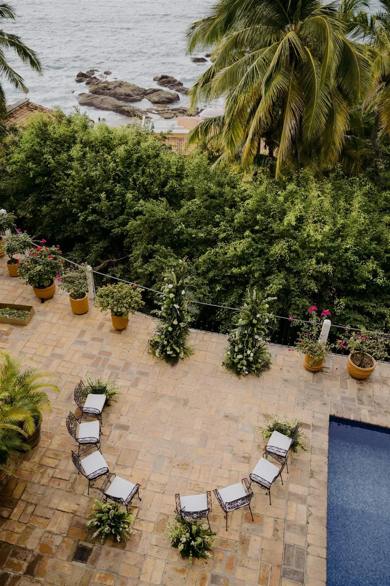 Intimate ceremony seating in a circle with white and green floral columns overlooking the ocean at Quinta de Los Leones