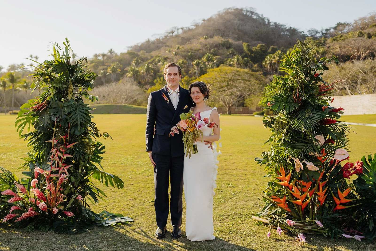 Couple framed by tropical installations on the polo field at Tierra Tropical