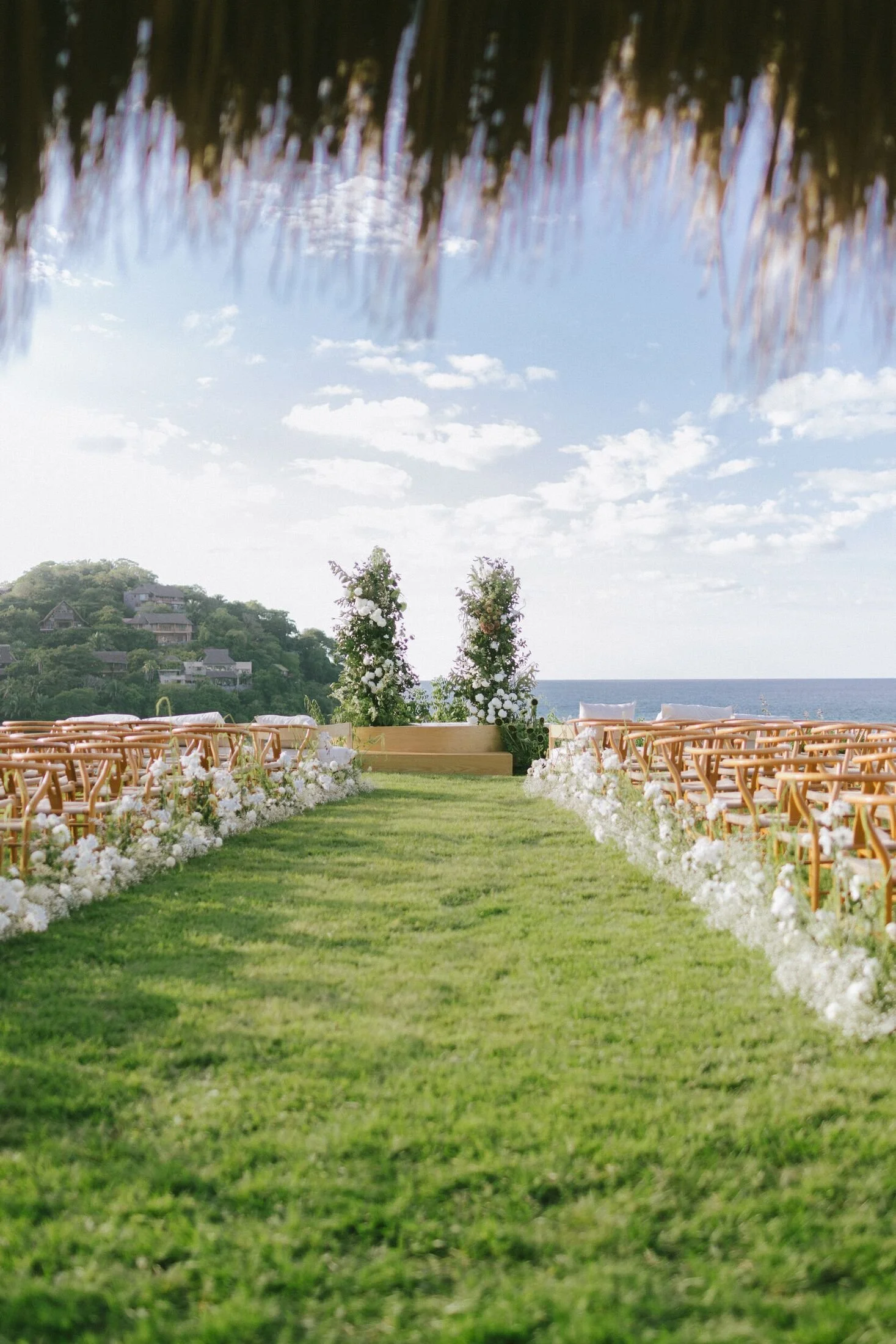 Ceremony aisle framed by topiaries above the ocean in Sayulita