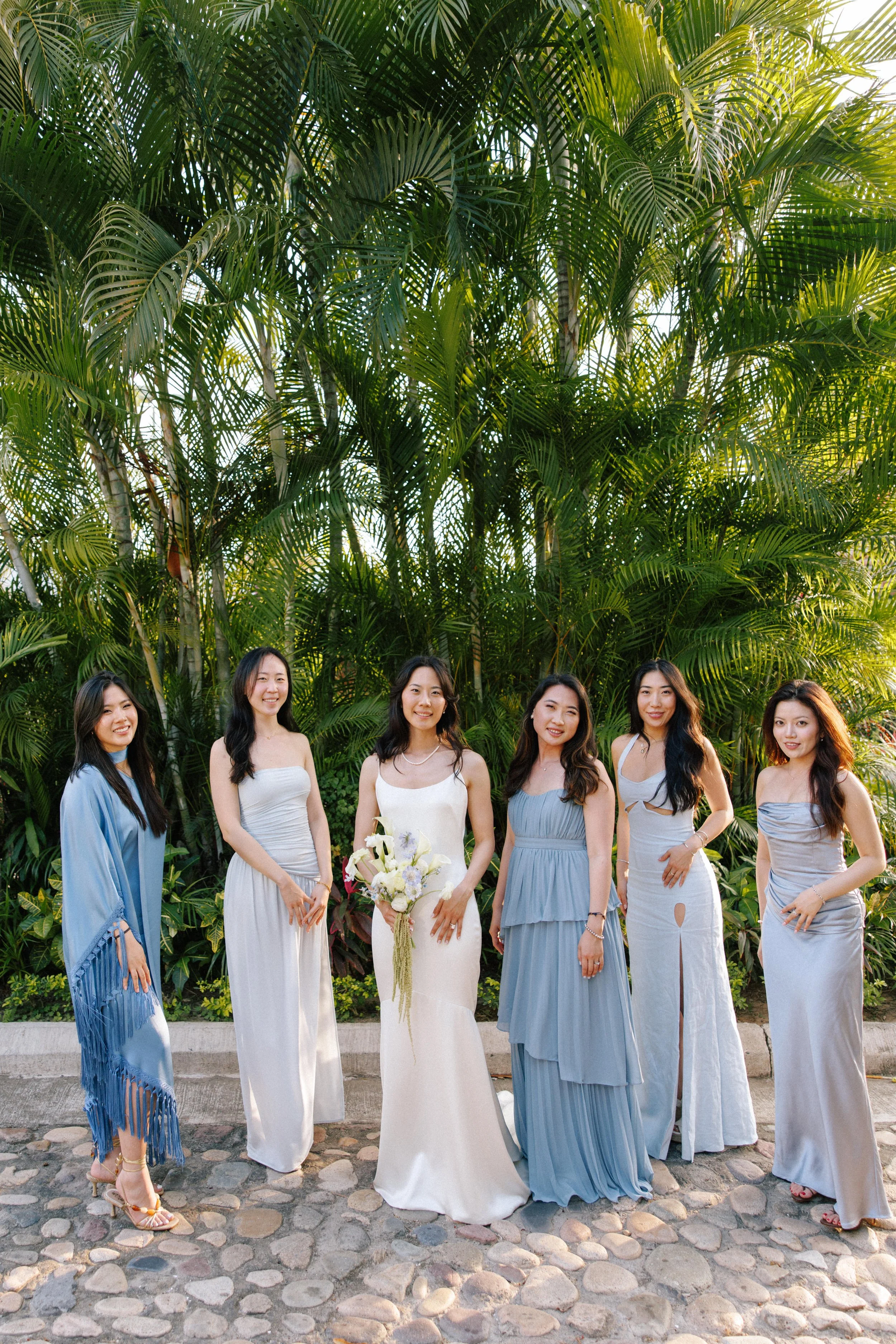 Bridesmaids in blue with white bouquets under the palms at Grand Miramar