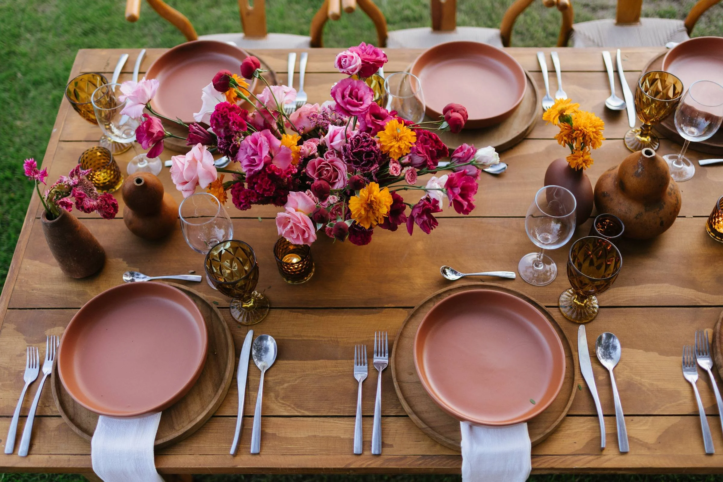 Overhead view of a Mexican wedding table in clay, amber glass and magenta florals