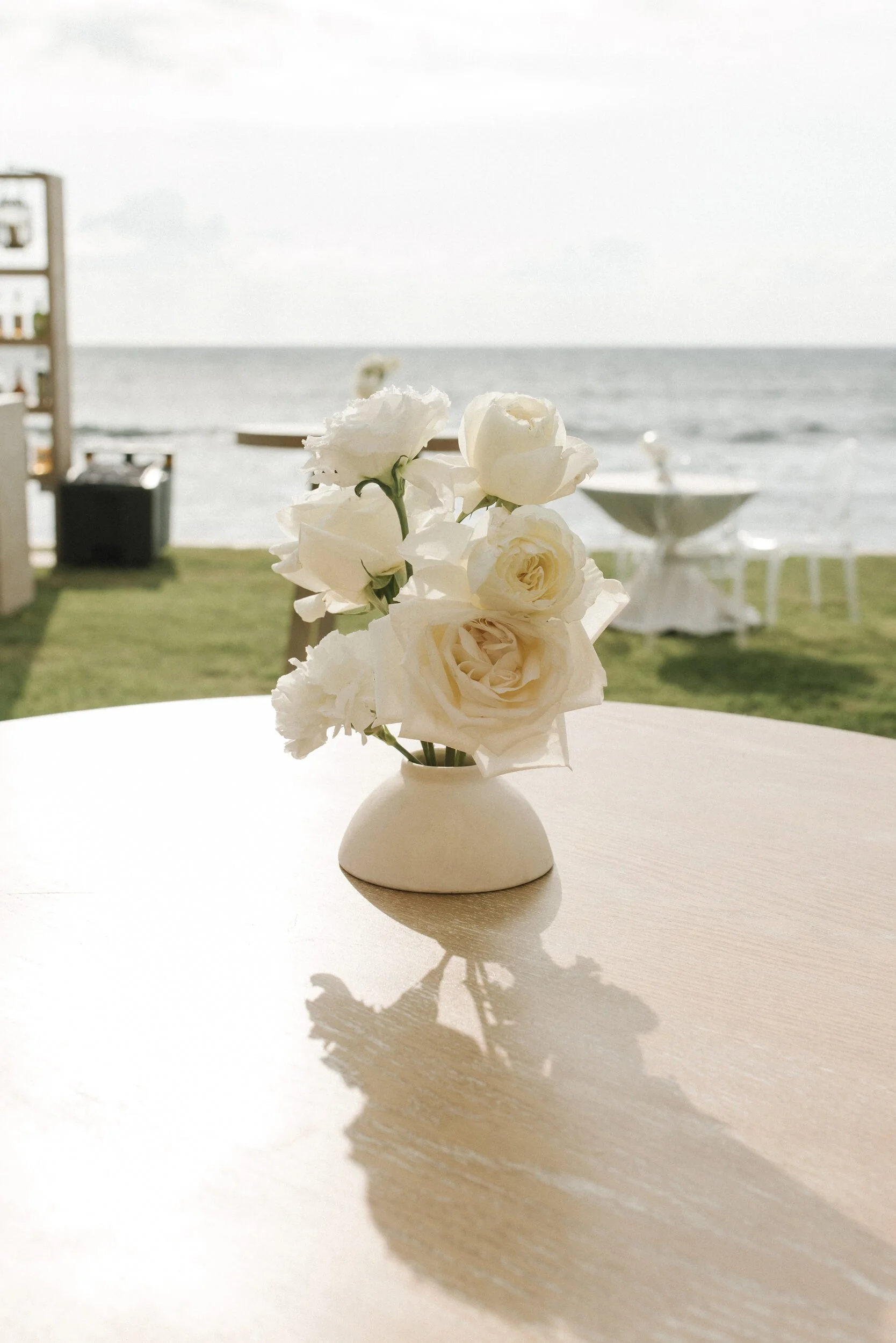 Cocktail table florals with the ocean behind it at Grand Velas