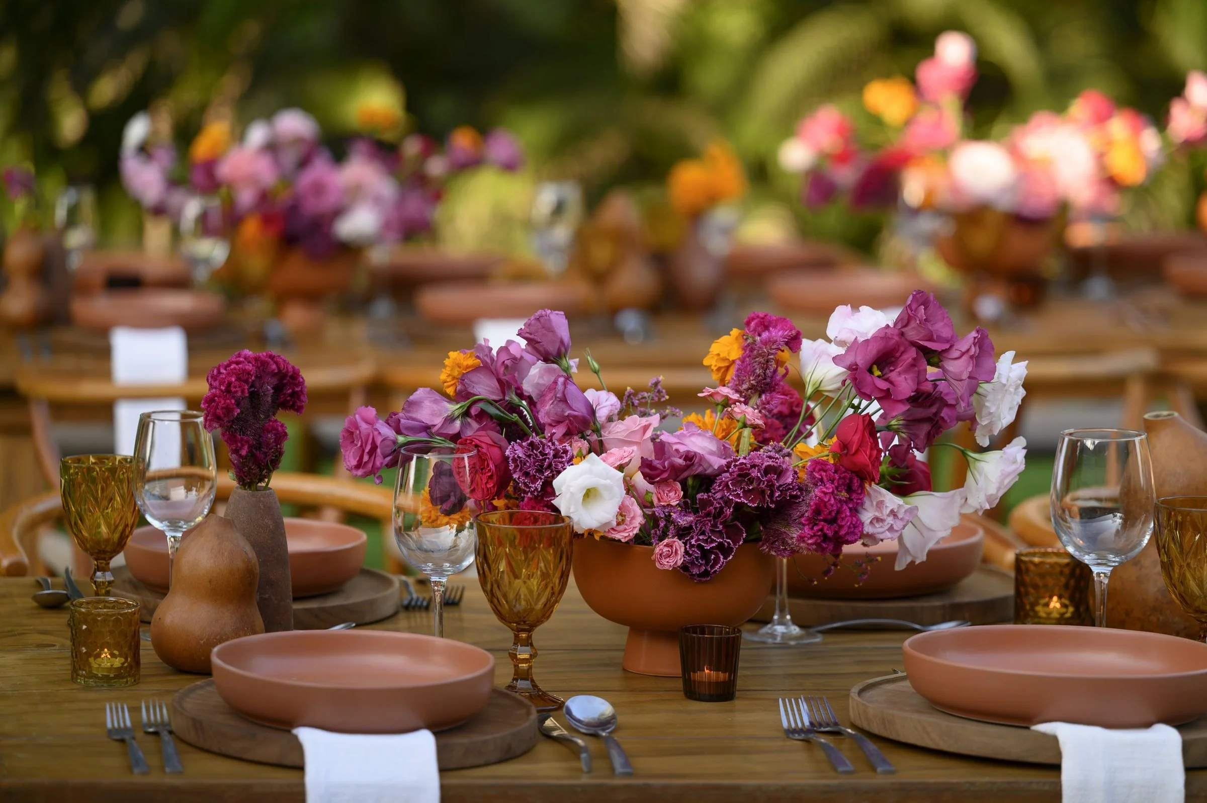 Tablescape in magenta and marigold against terracotta and raw wood