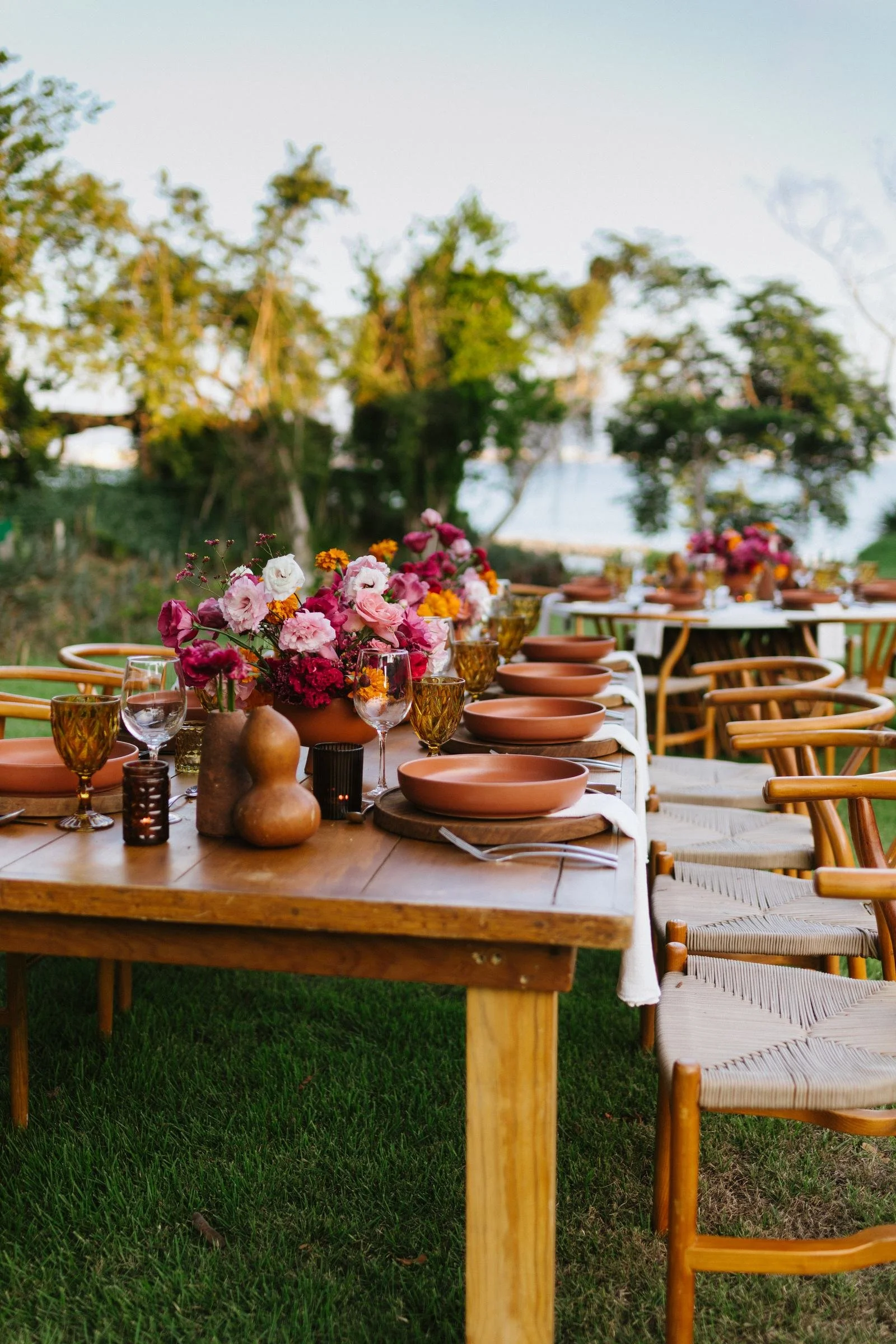 Wedding table in clay and magenta framed by palms and a white wall
