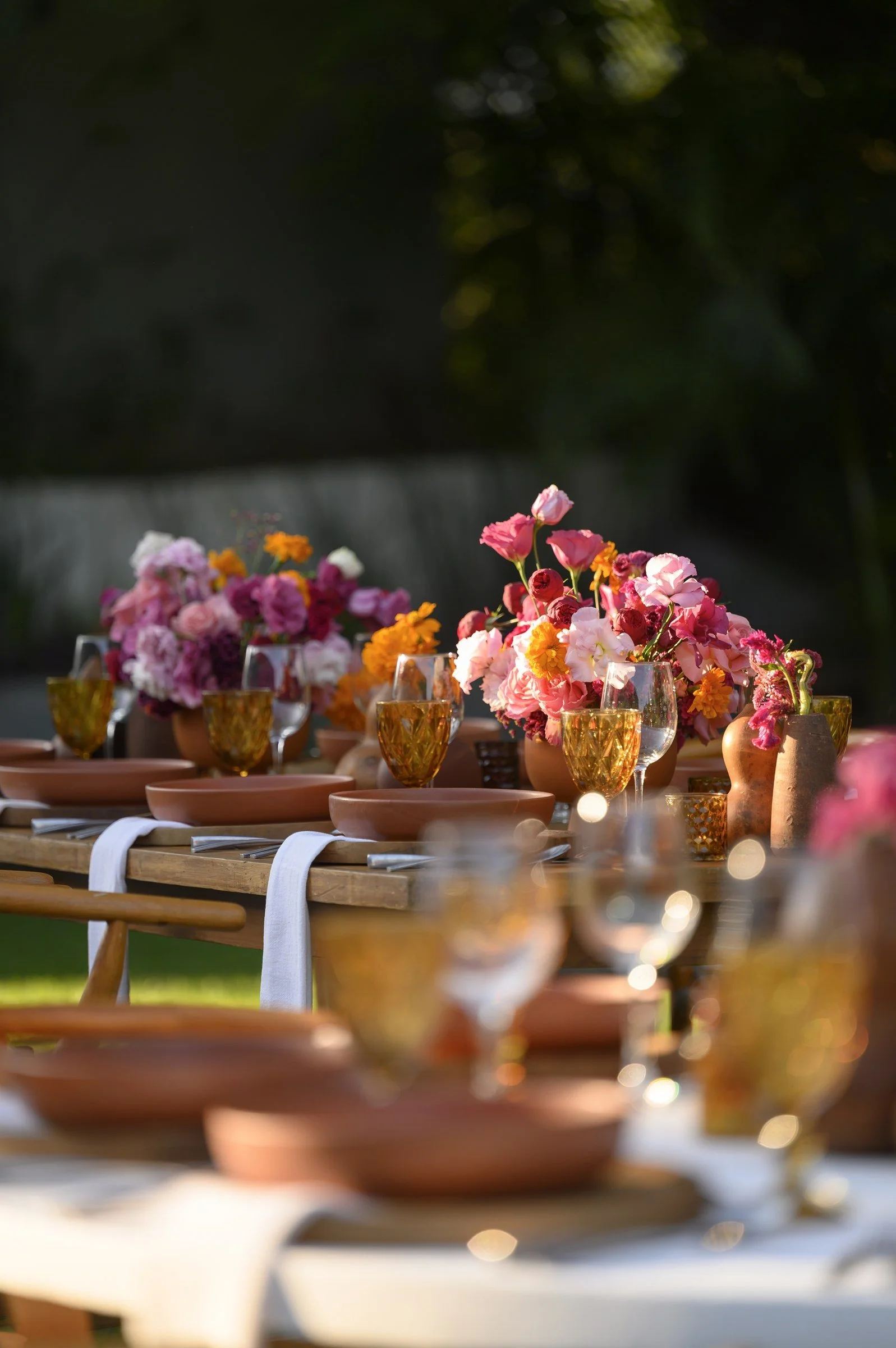 Compotes of magenta and coral repeating down the length of a wedding table