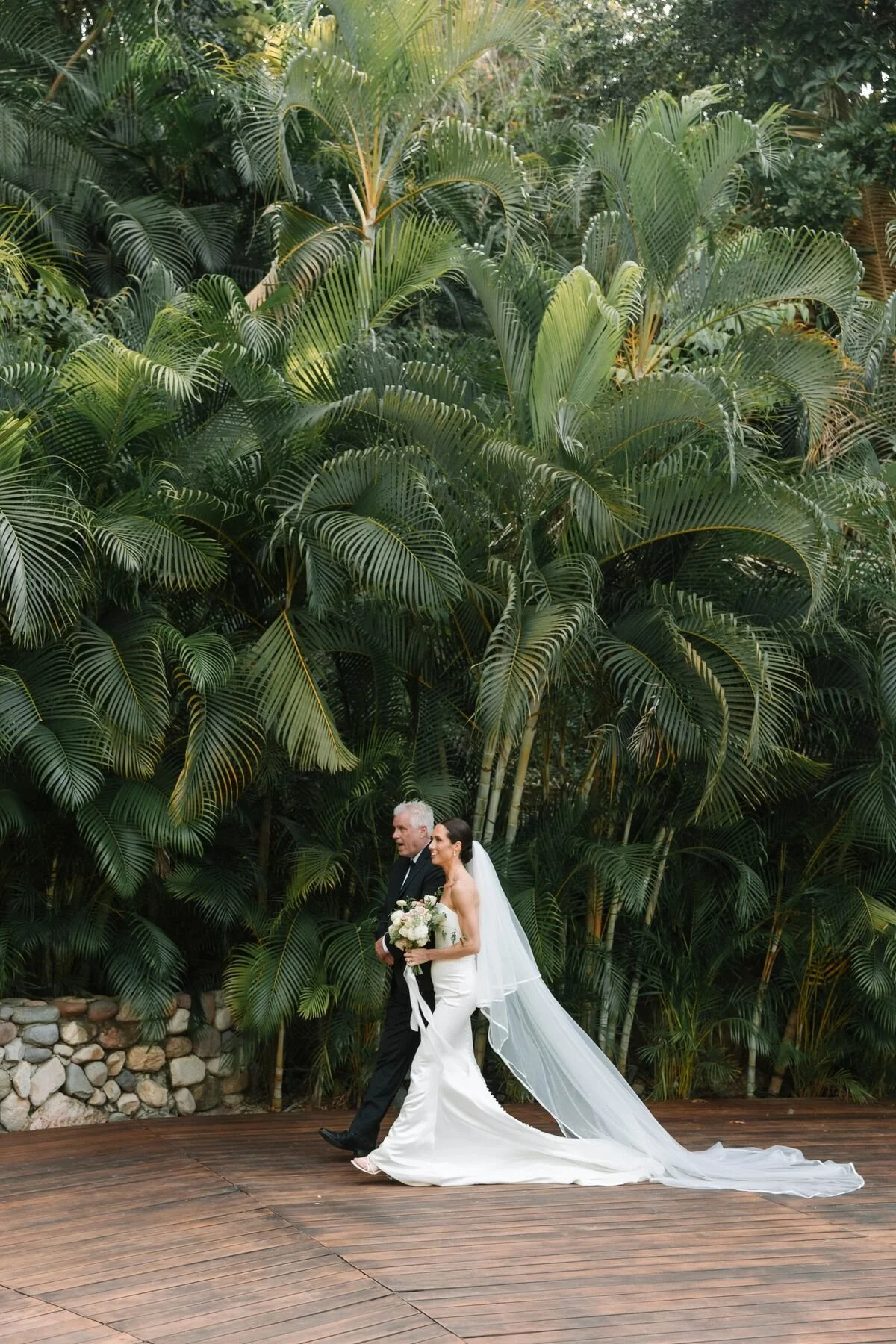 Bride walking down the aisle against a wall of palms at Garza Blanca The Forum