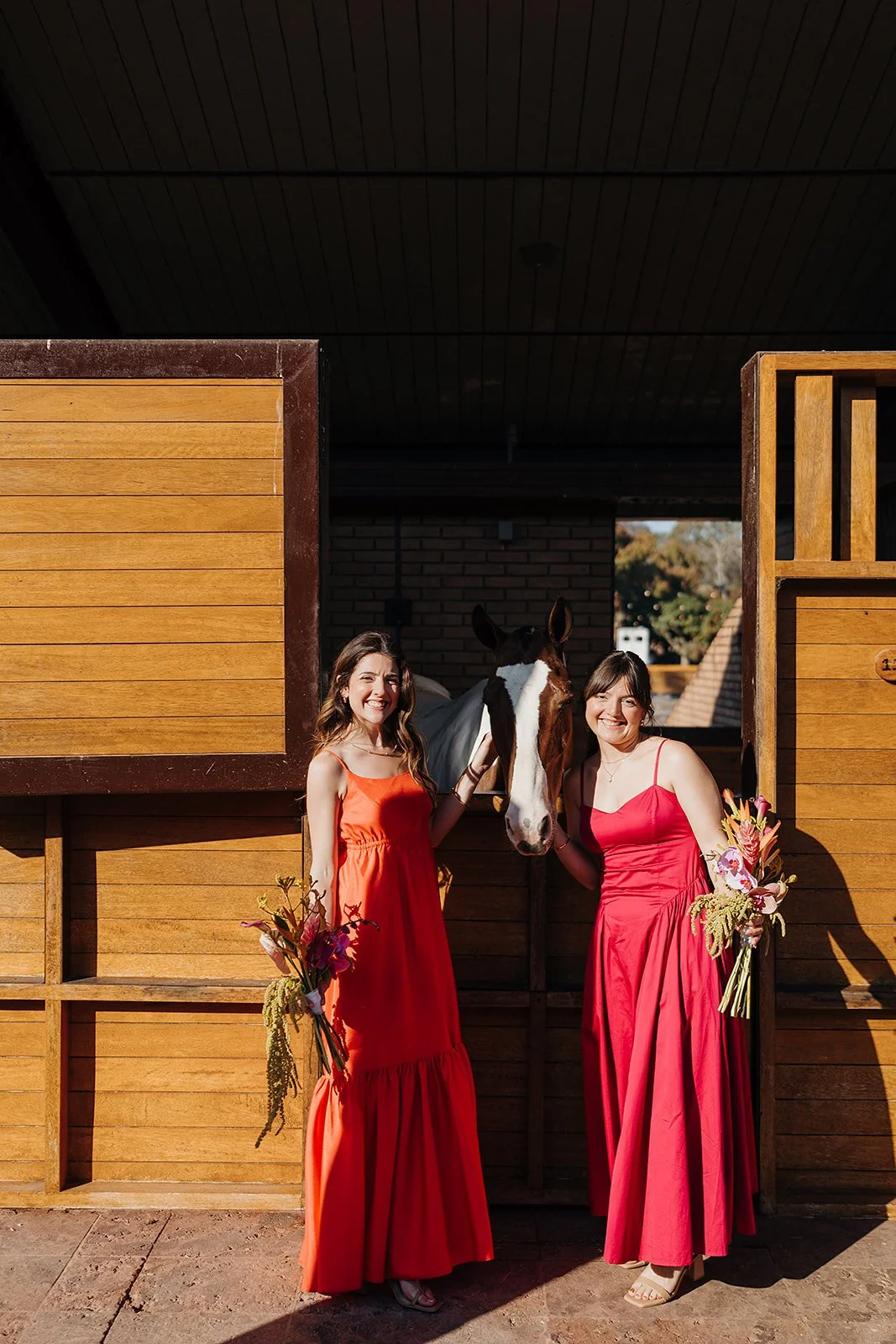 Bridesmaids with tropical bouquets beside a horse at the Tierra Tropical Polo Club stables