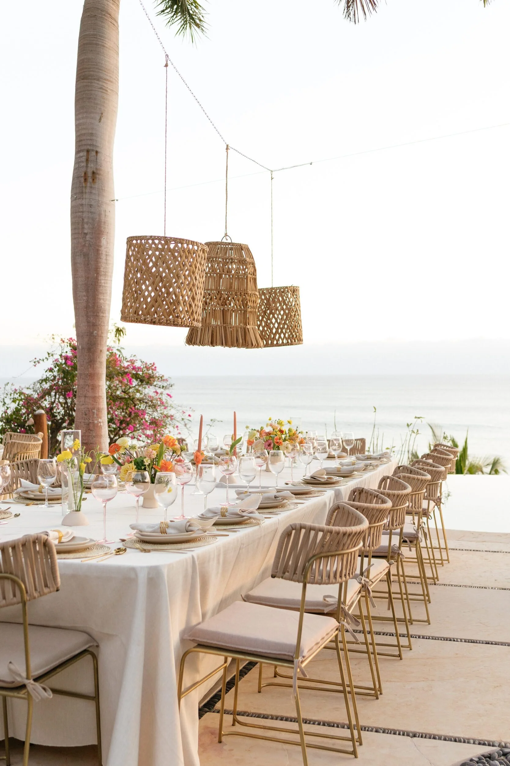 Long table under rattan pendants above the ocean at a Punta de Mita villa