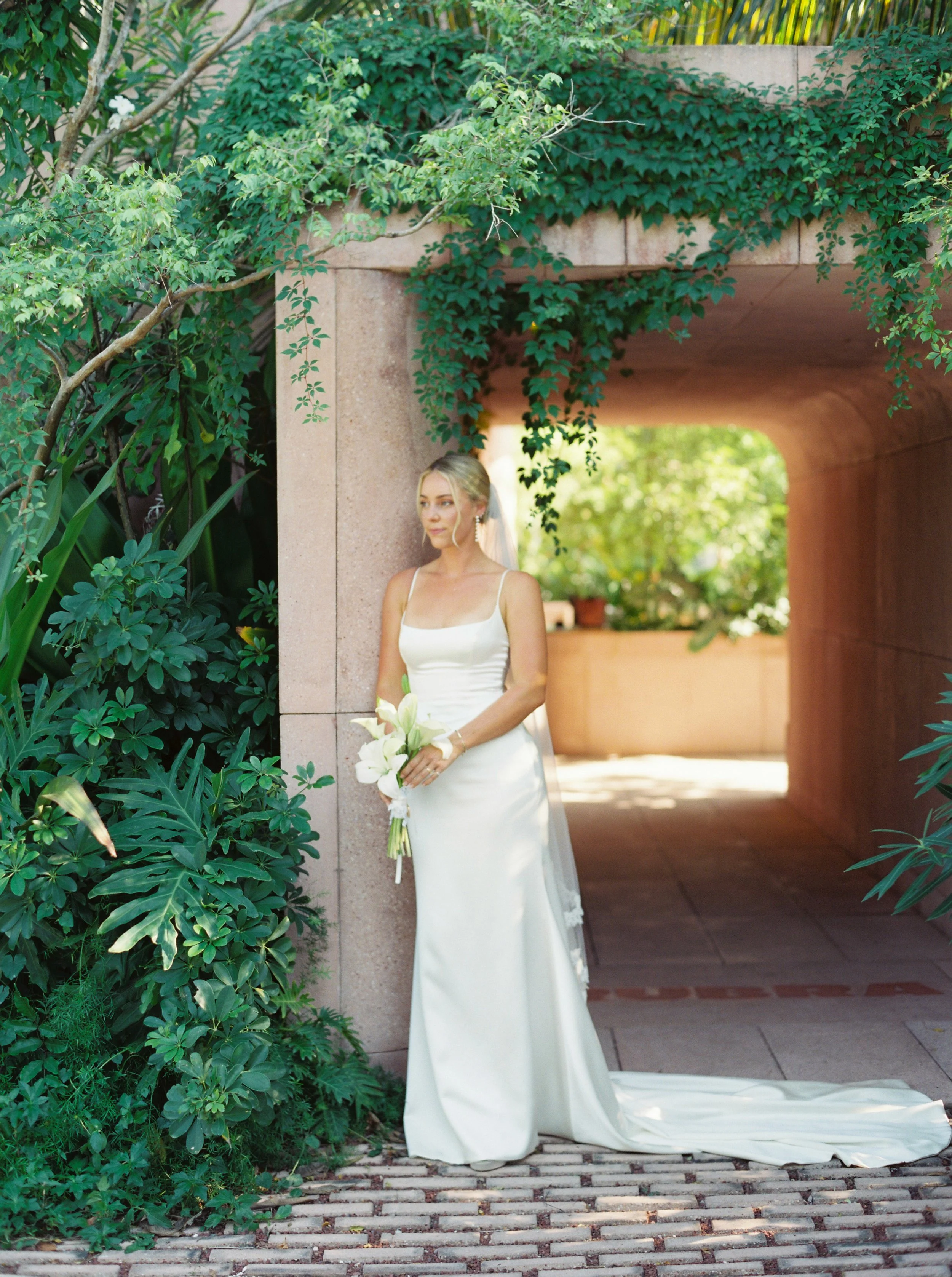Bride with her white calla lily bouquet against a stone column at W Punta de Mita
