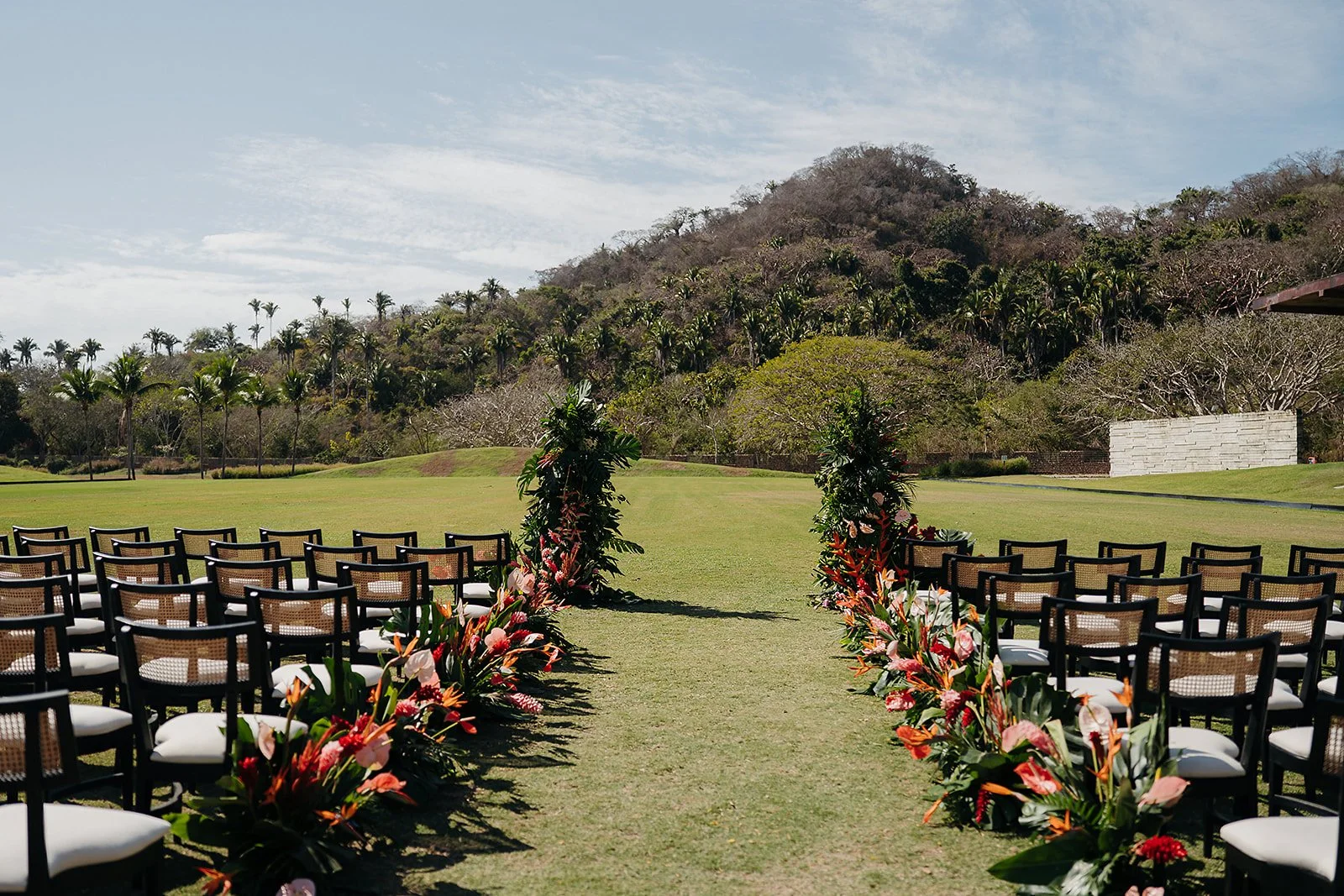 Ceremony aisle lined with tropical florals at Tierra Tropical Polo Club, San Pancho