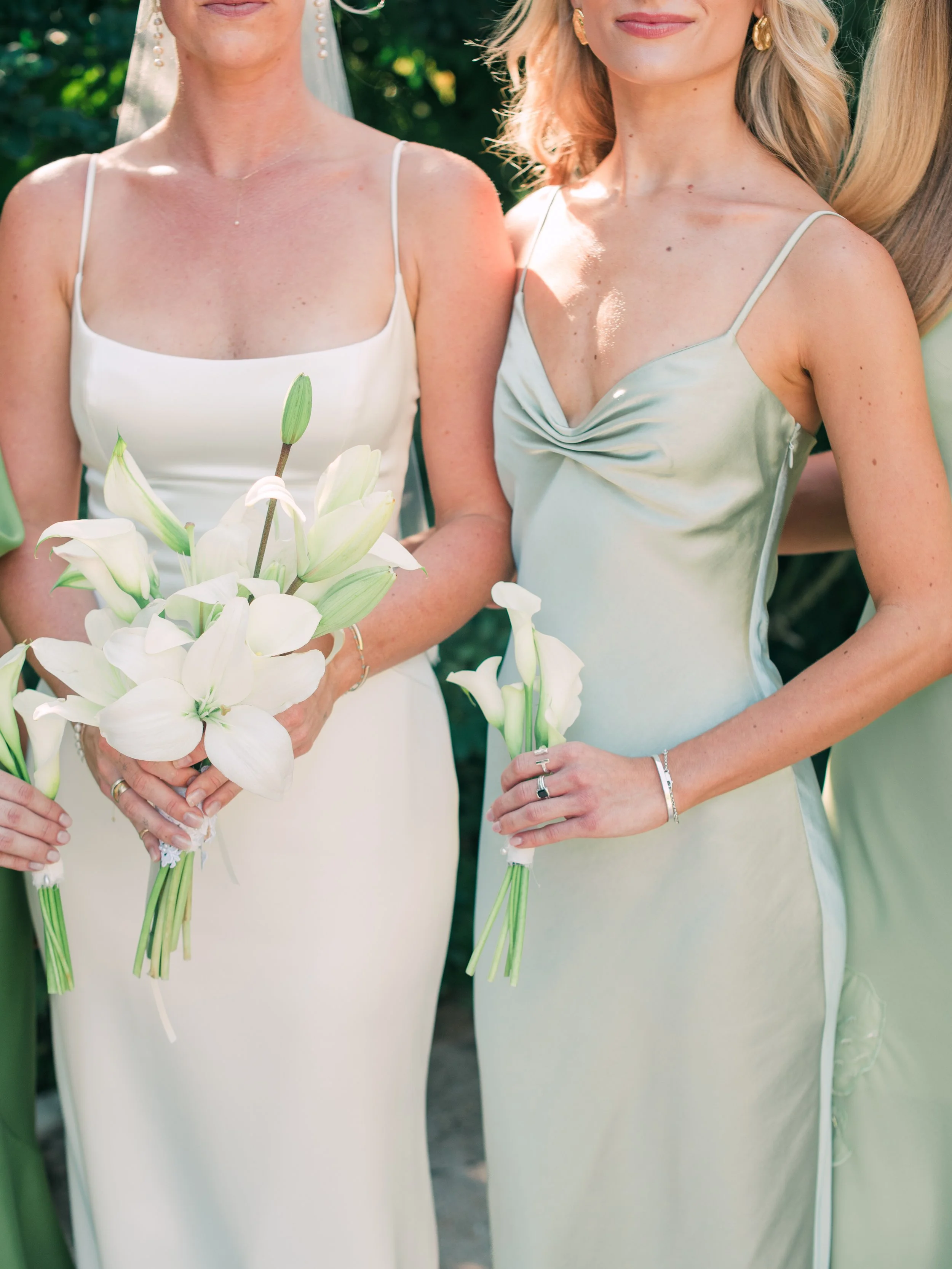 Detail of the bride's white lily bouquet beside a bridesmaid's calla at W Punta de Mita