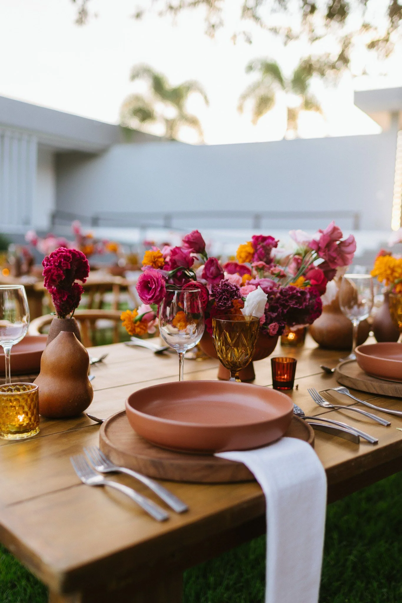 Wedding table in clay and magenta framed by palms and a white wall