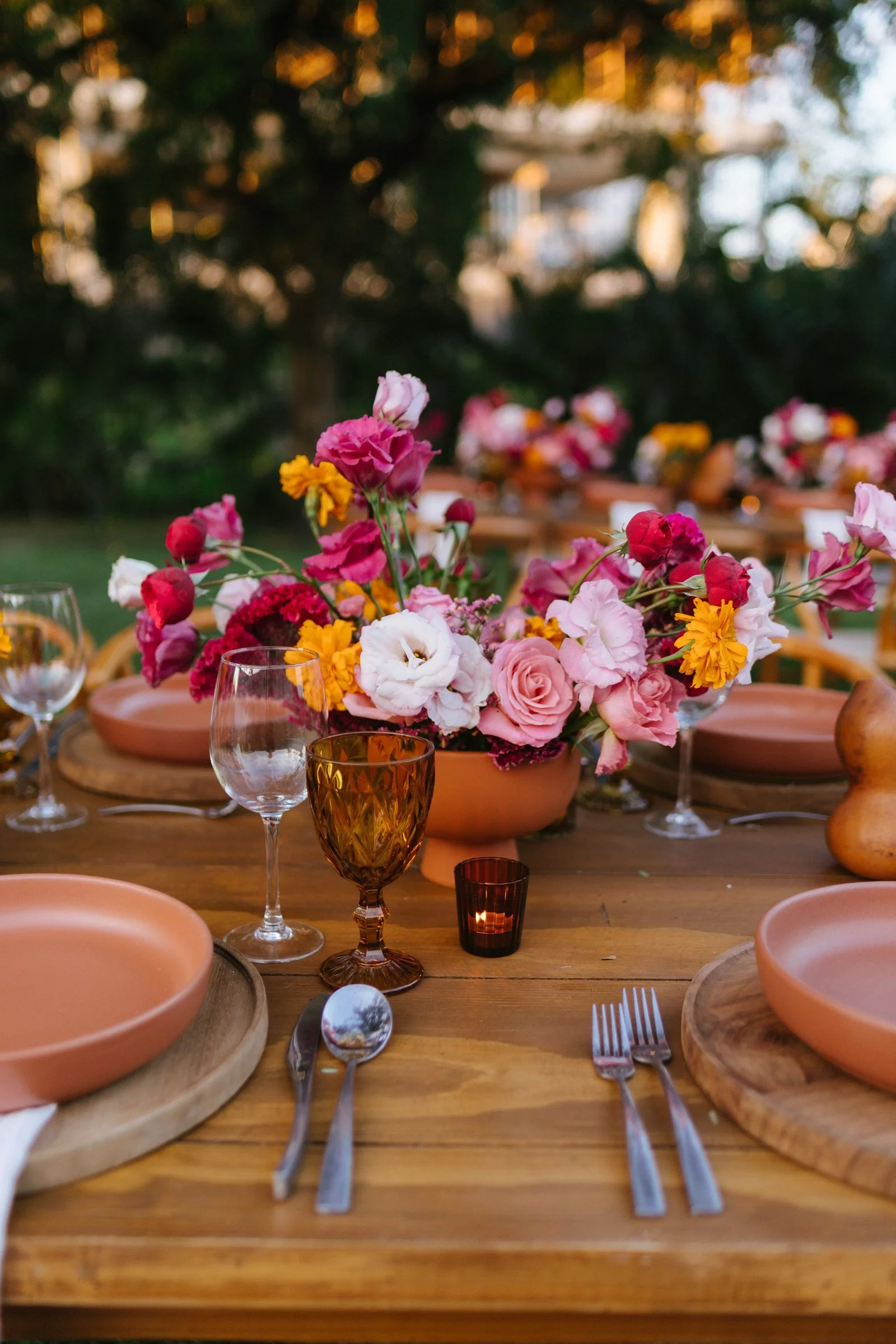 Magenta centerpiece and amber glass catching the last light of golden hour