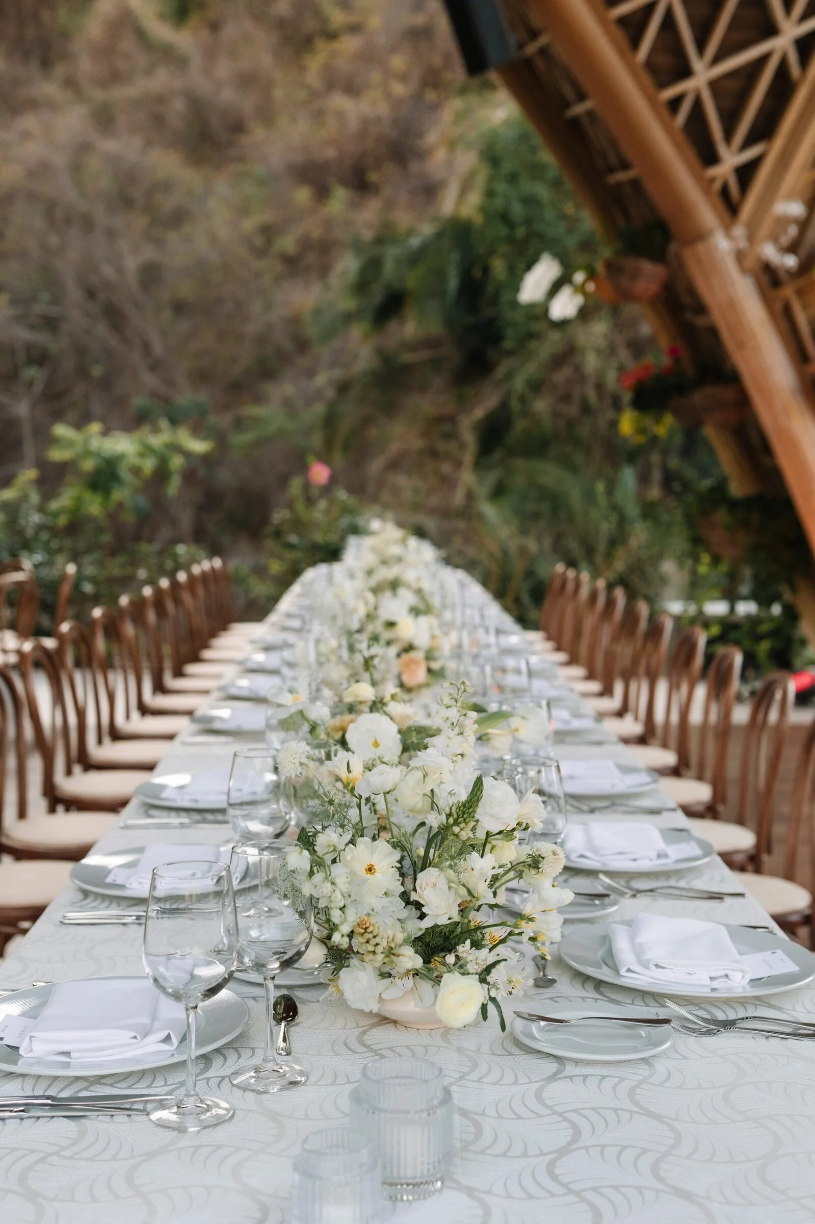 Long table below hanging orchid baskets at The Forum pavilion in Garza Blanca