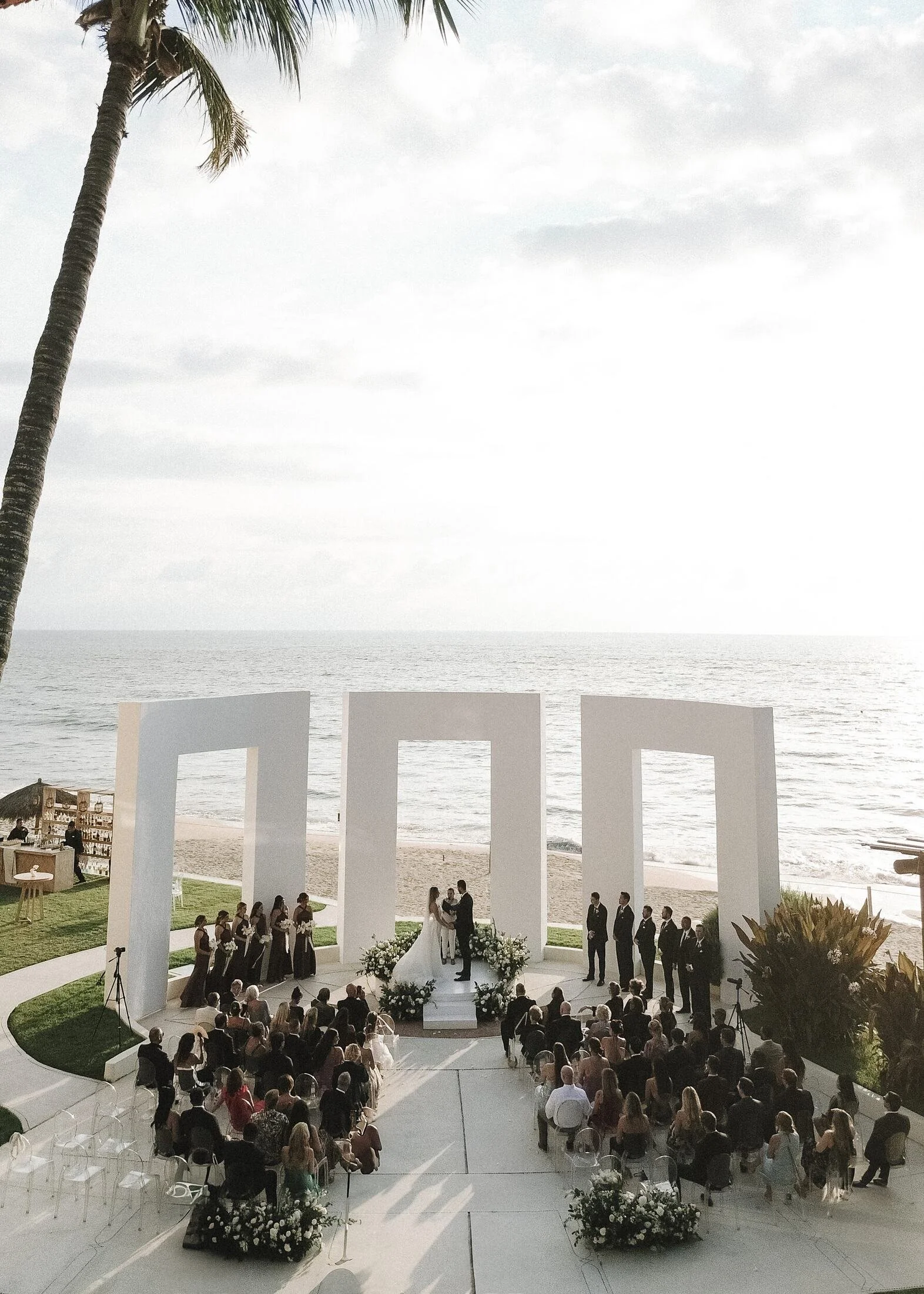 Aerial view of a white portal wedding ceremony on the beachfront lawn at Grand Velas