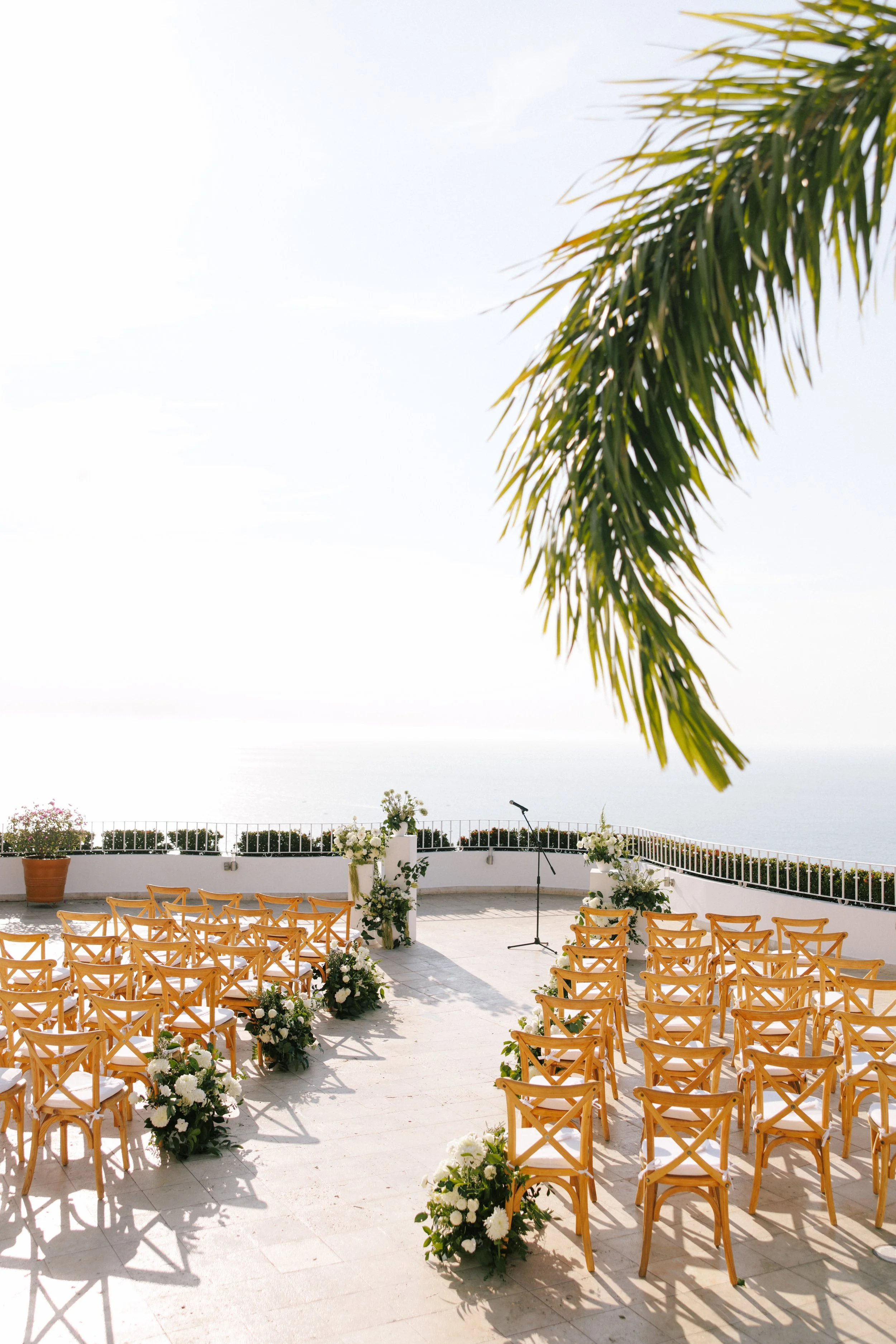 Ceremony set on the terrace under a palm frond above Banderas Bay at Grand Miramar