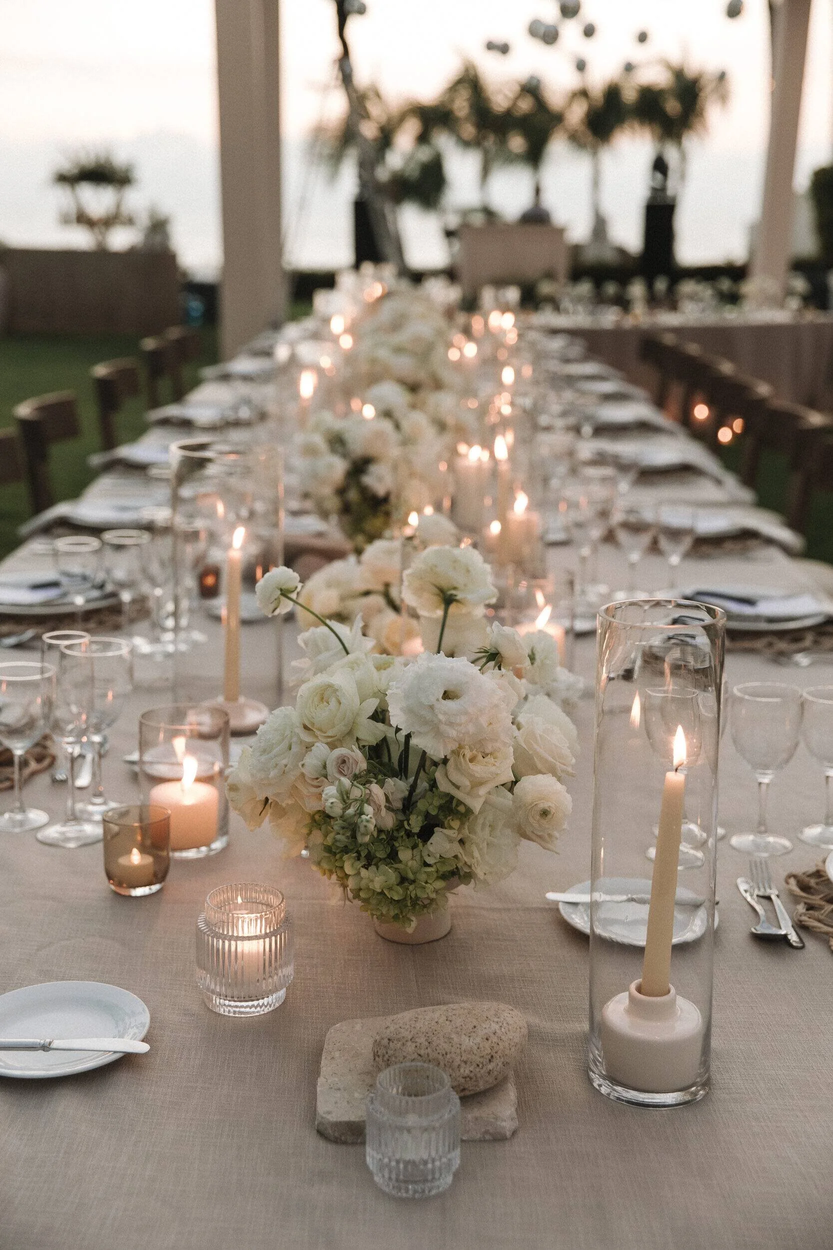 Long table with white ranunculus and candlelight at Grand Velas Riviera Nayarit