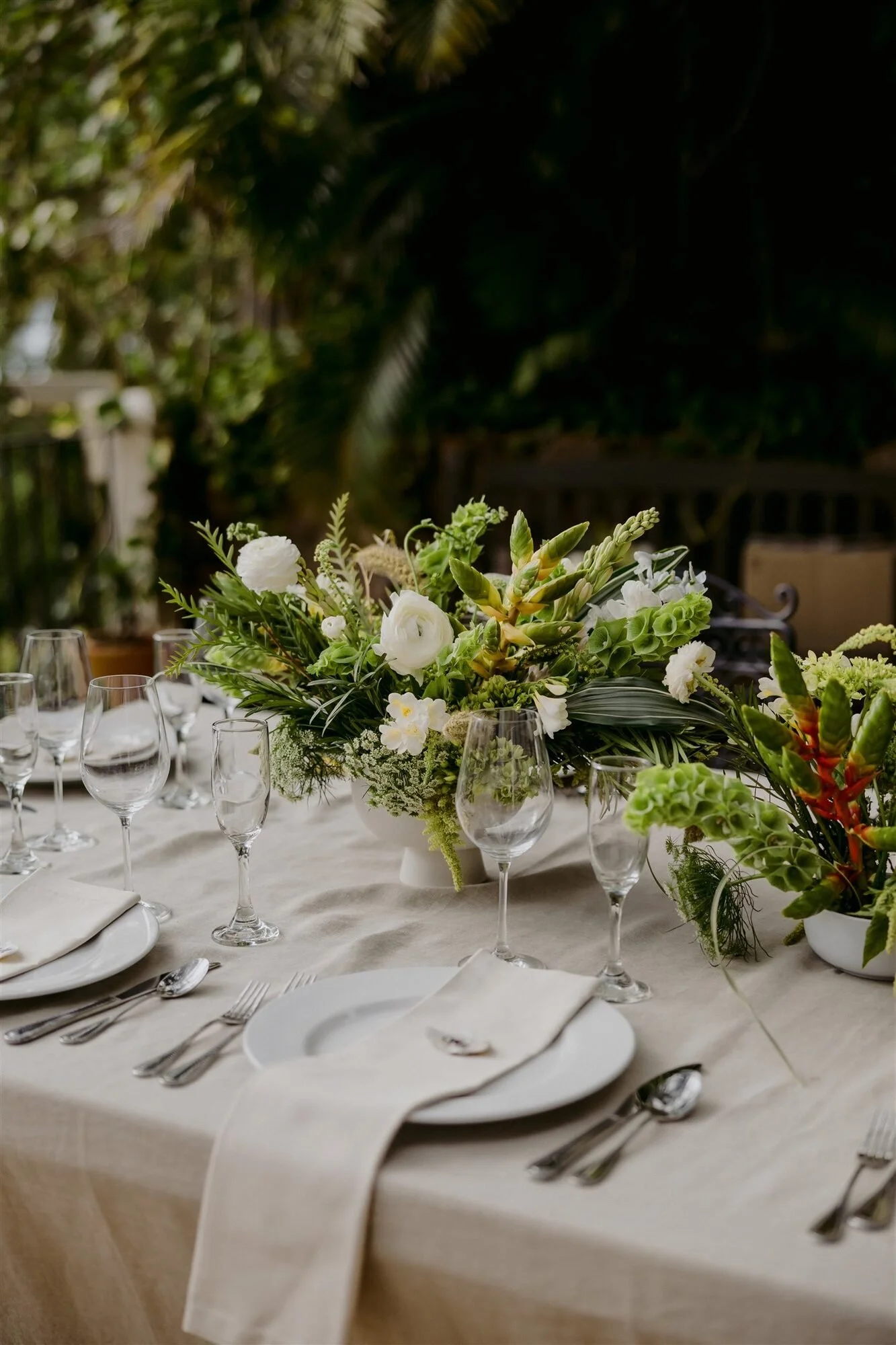 Low white and green centerpiece in a white footed compote by Flowers by JJ