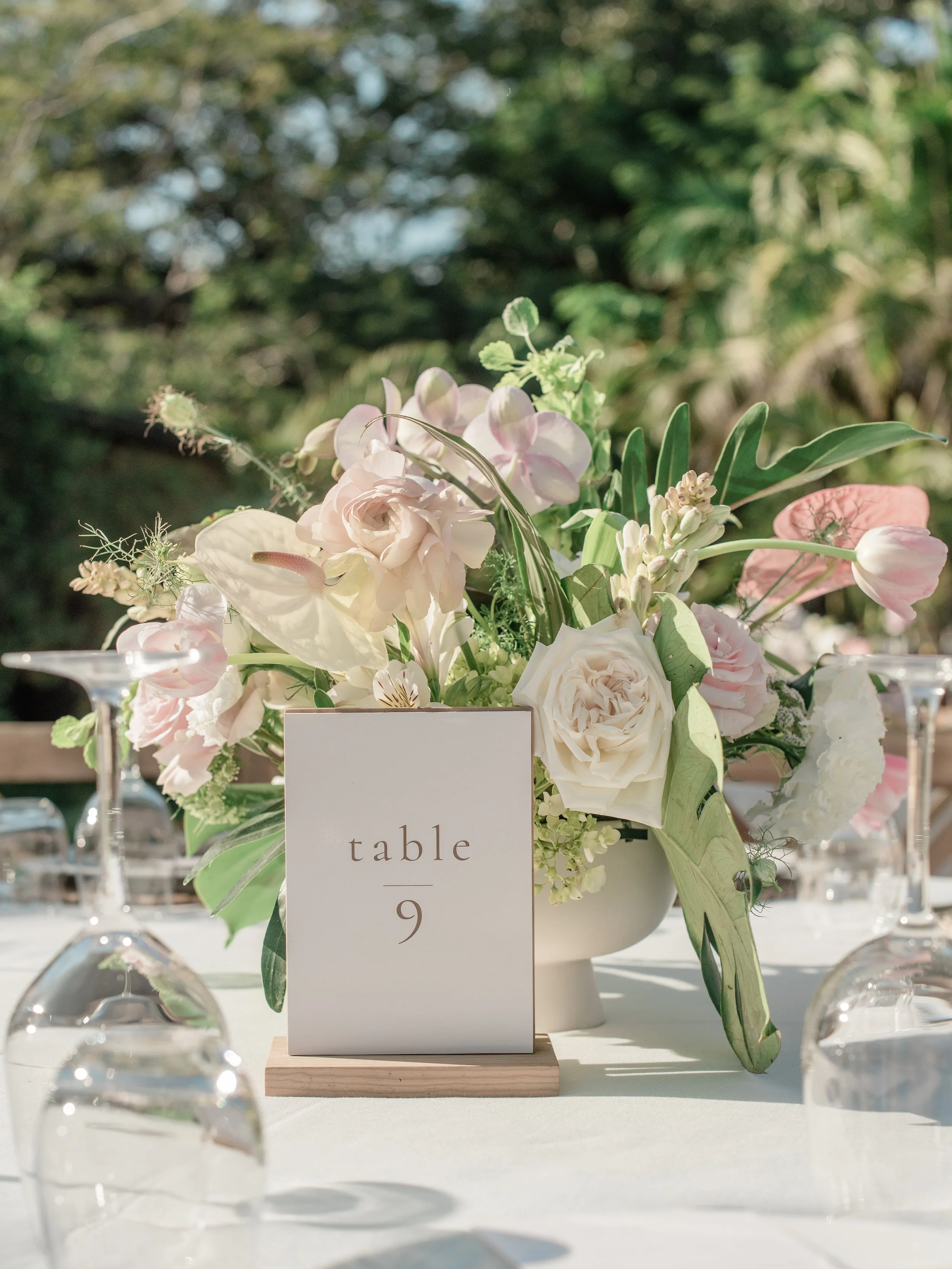 Centerpiece of white anthurium, orchid and tulip beside a table number at W Punta de Mita