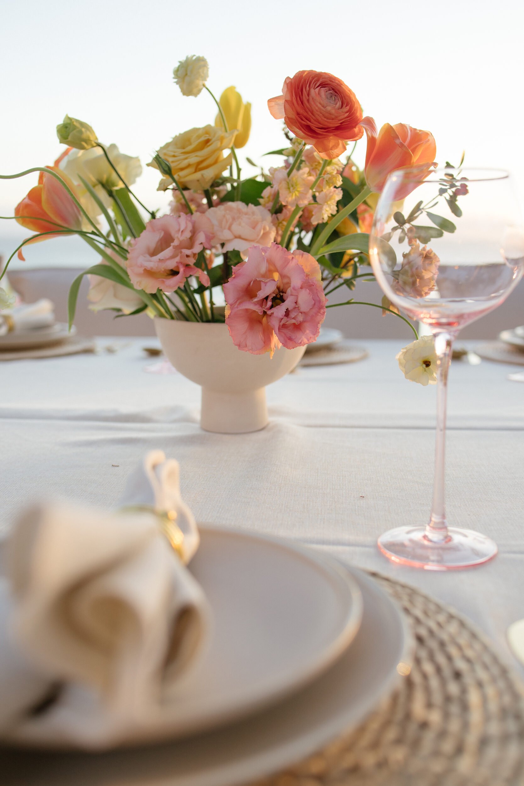 Coral and peach centerpiece beside a rattan place setting, Punta de Mita