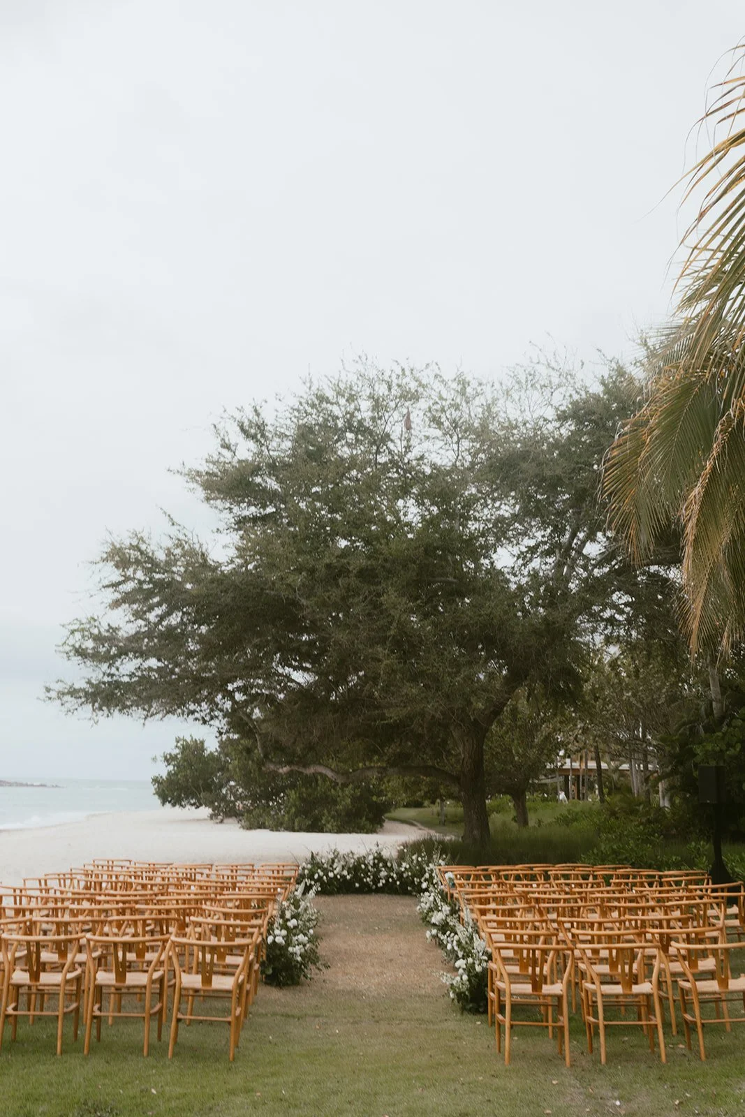 Aisle lined with white roses and greenery at a Punta Mita beach ceremony