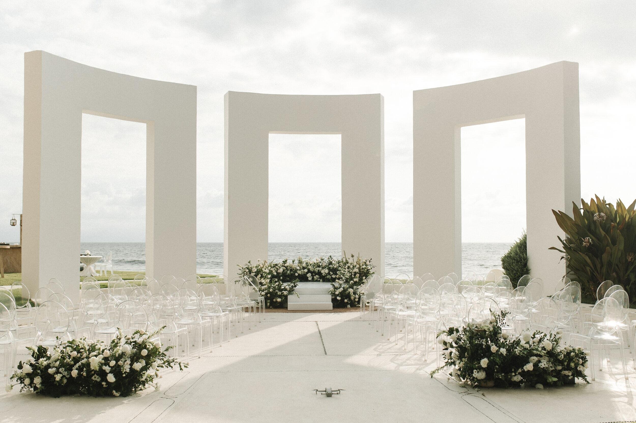 White ceremony portals with grounded white florals at Grand Velas Riviera Nayarit