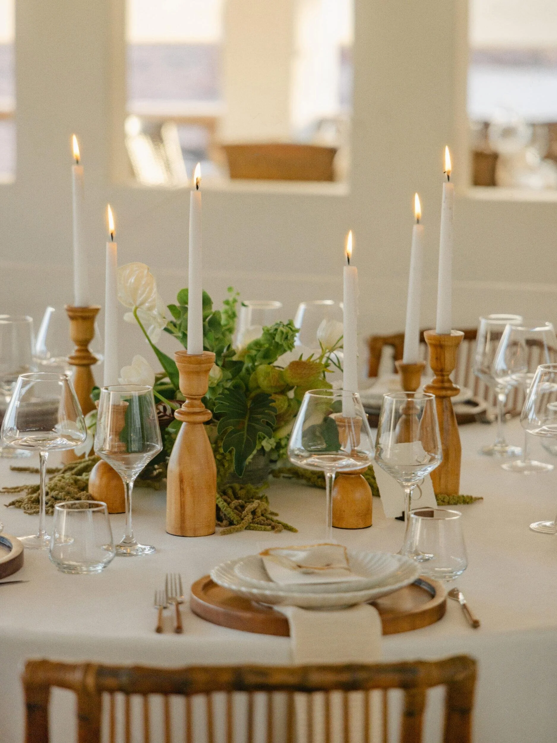 Low white and green centerpiece with wooden taper candles at a Casa Kimberly wedding
