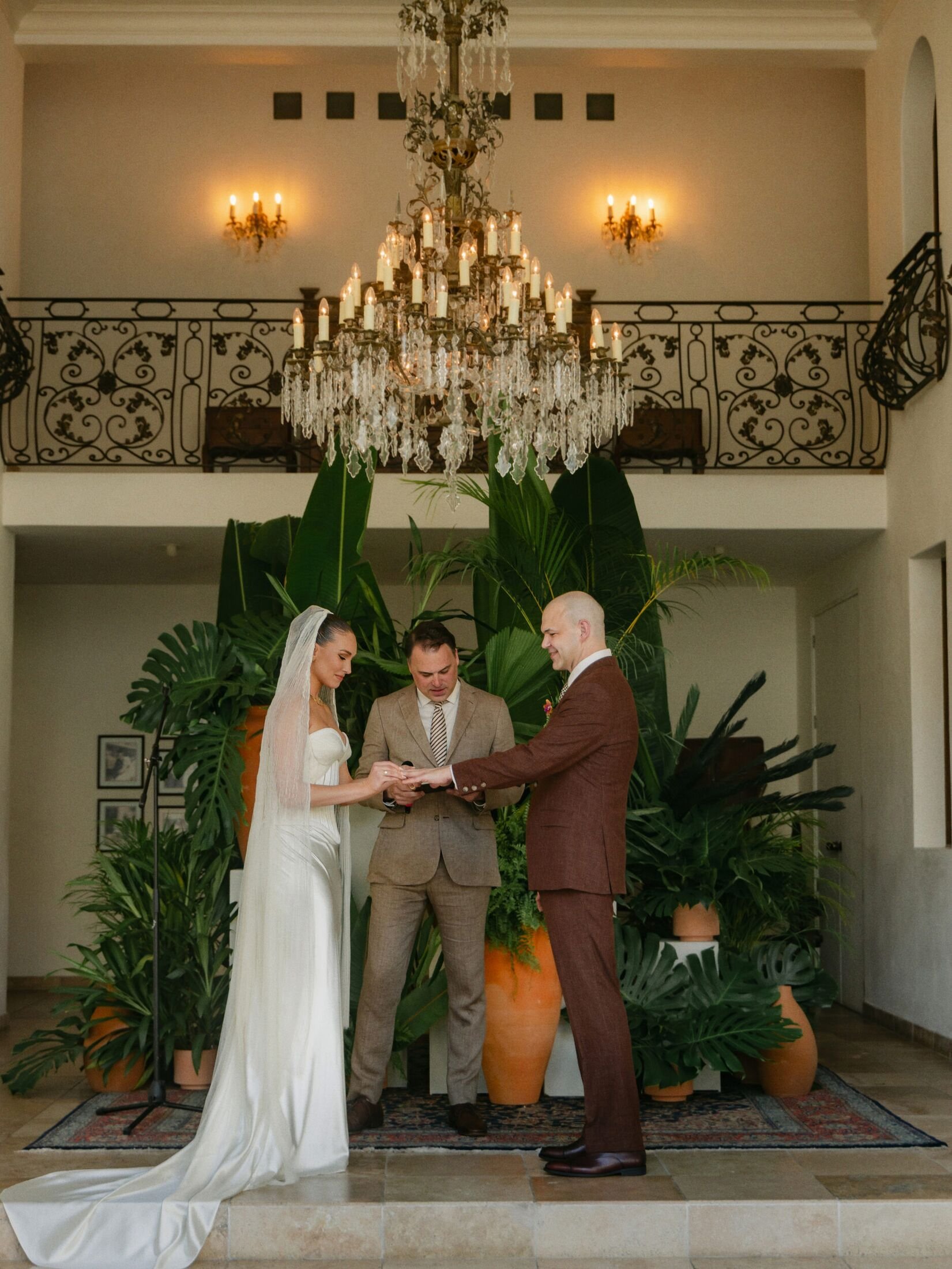 Couple exchanging rings before a tropical terracotta backdrop at Casa Kimberly