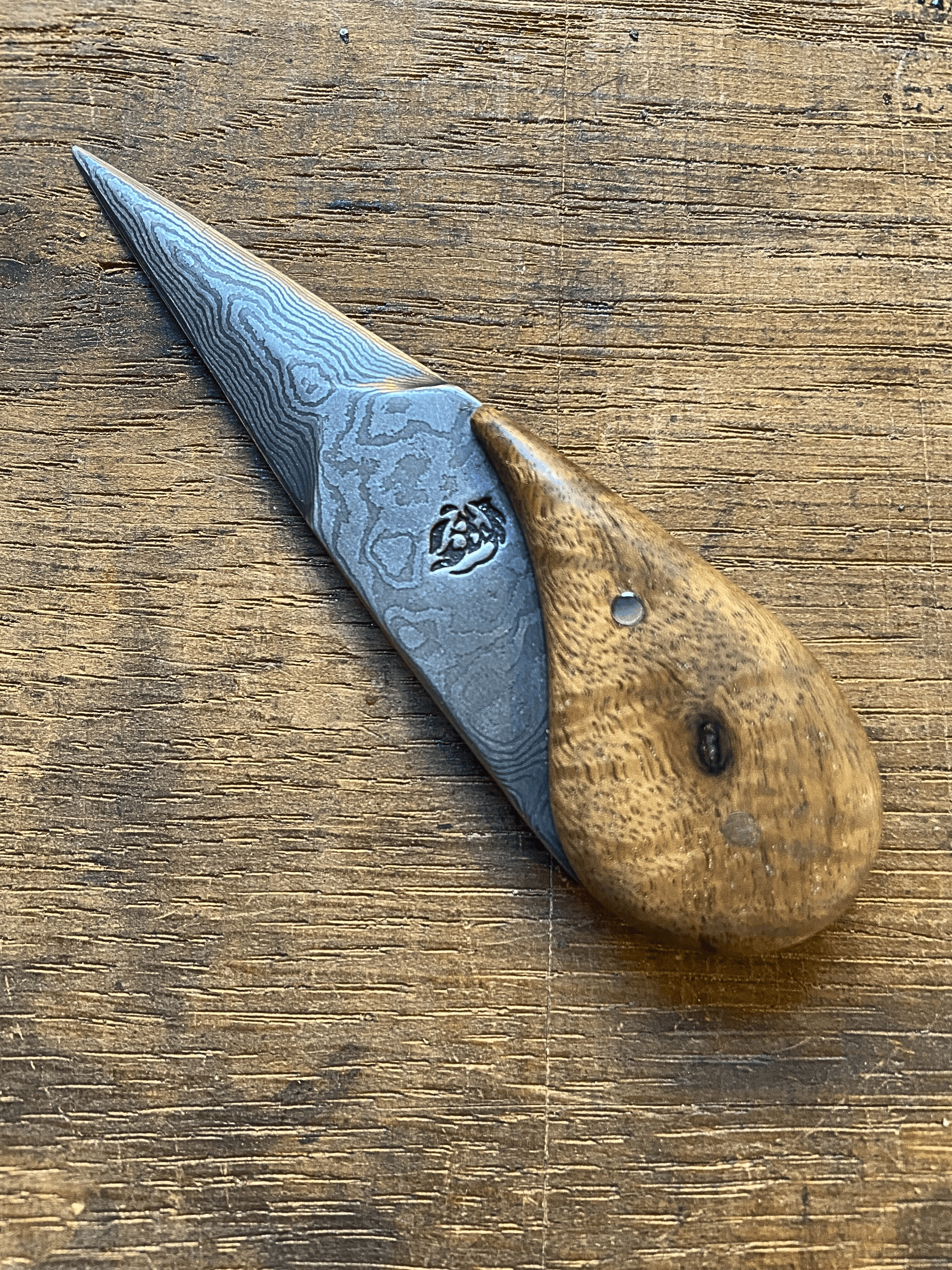 Couteau Ouvre Huïtres Damassé avec manche en bois de chêne clair sur fond de bois de chêne.