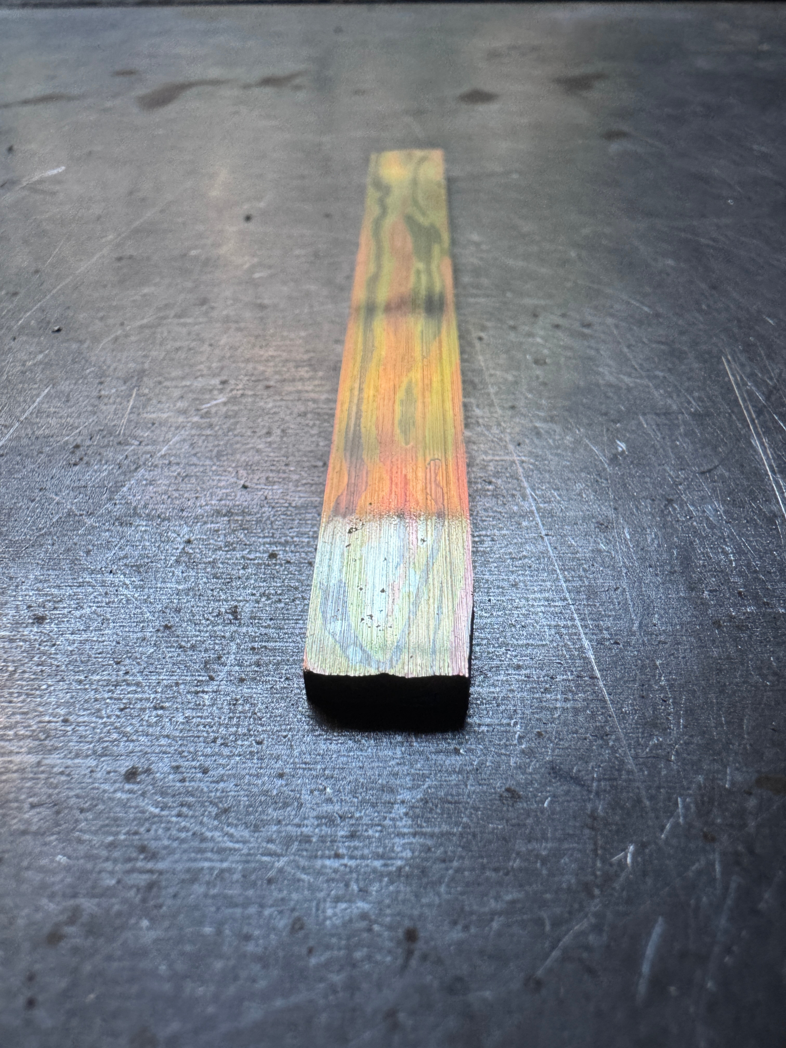 Une pièce de métal imitation bois, avec une coloration irisée sur toute sa surface.