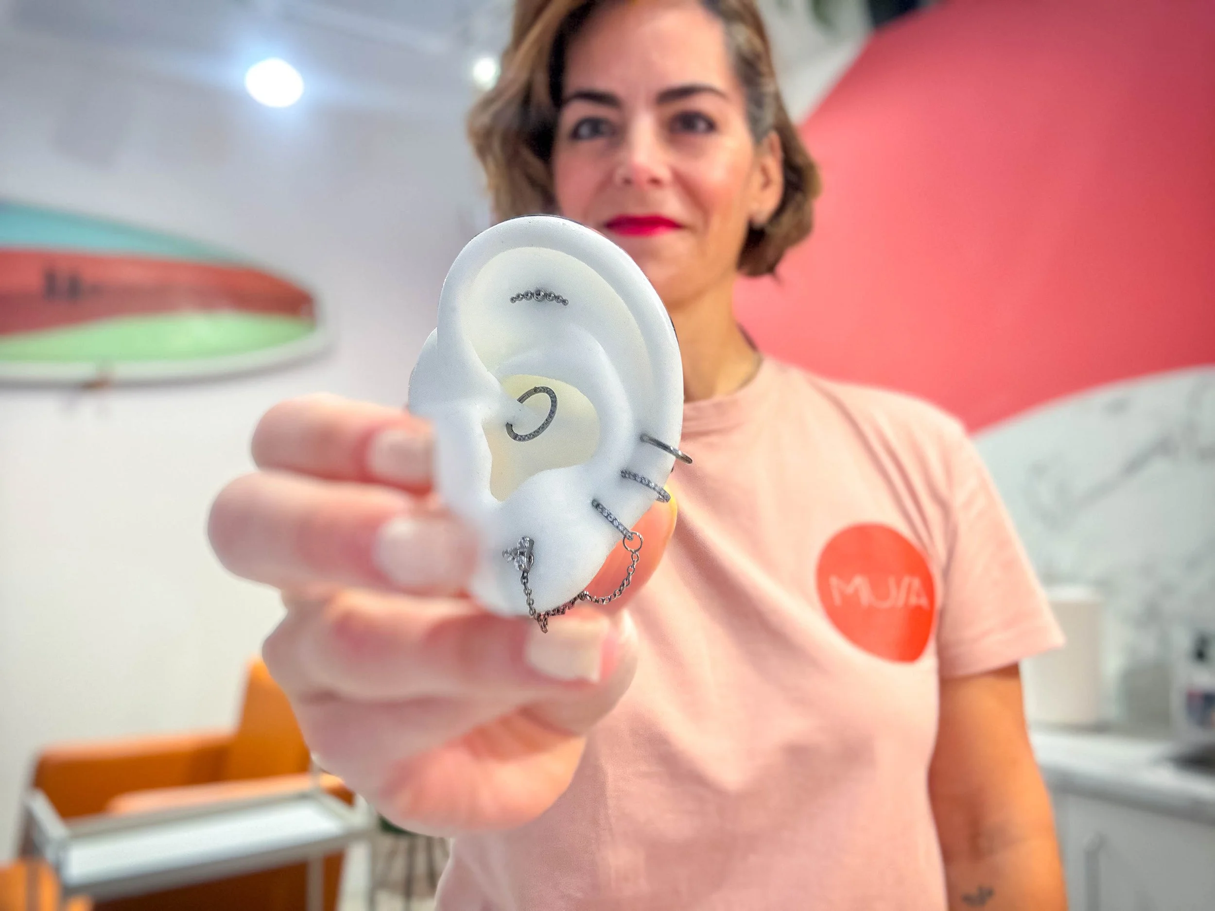 Jone Larragain, piercer profesional, sujetando una oreja de goma con un diseño en piezas de titanio certificado.