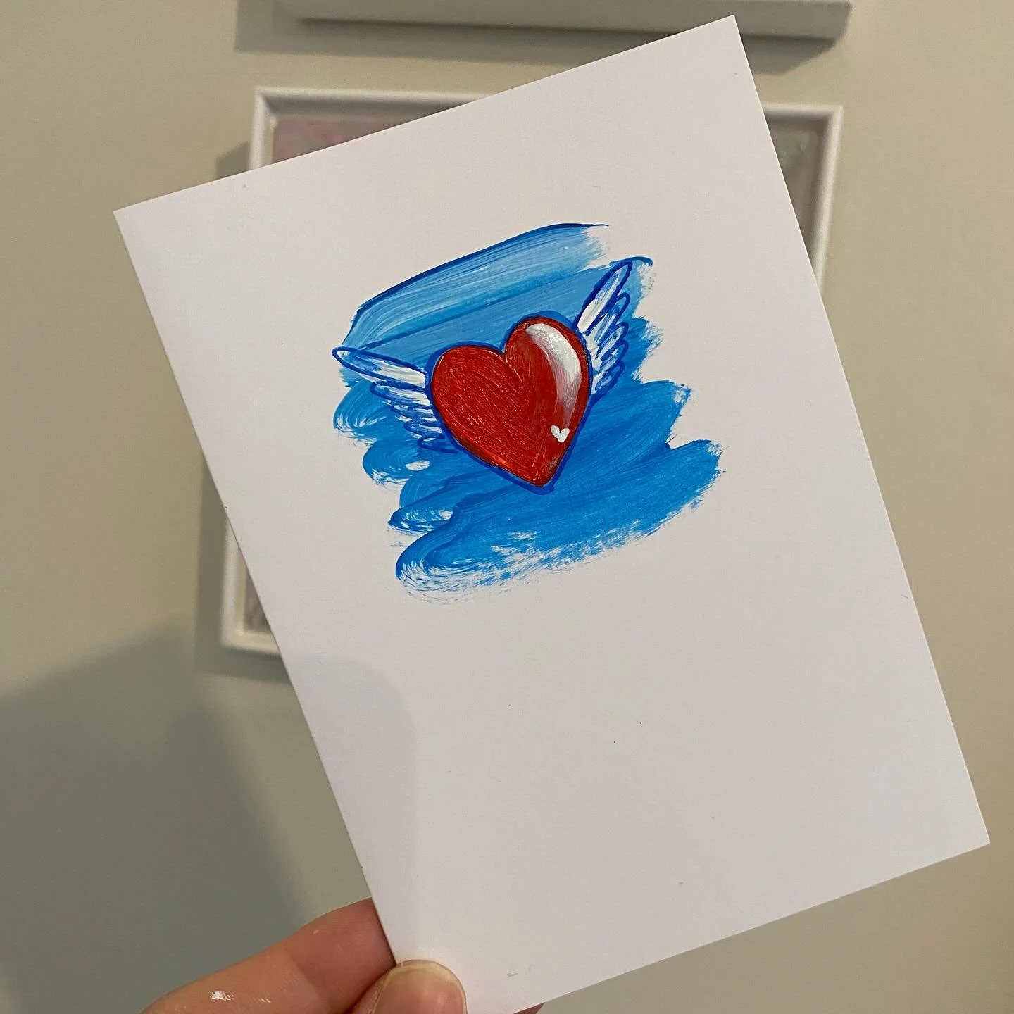 Hot off the press! Hand-painted winged heart card! ❤️🪽💙. #nickyluck #nickyluckart #wingedheart #handpaintedcard #minioriginal #redheart #heartpainting #wingedheartpainting #loveconquersall