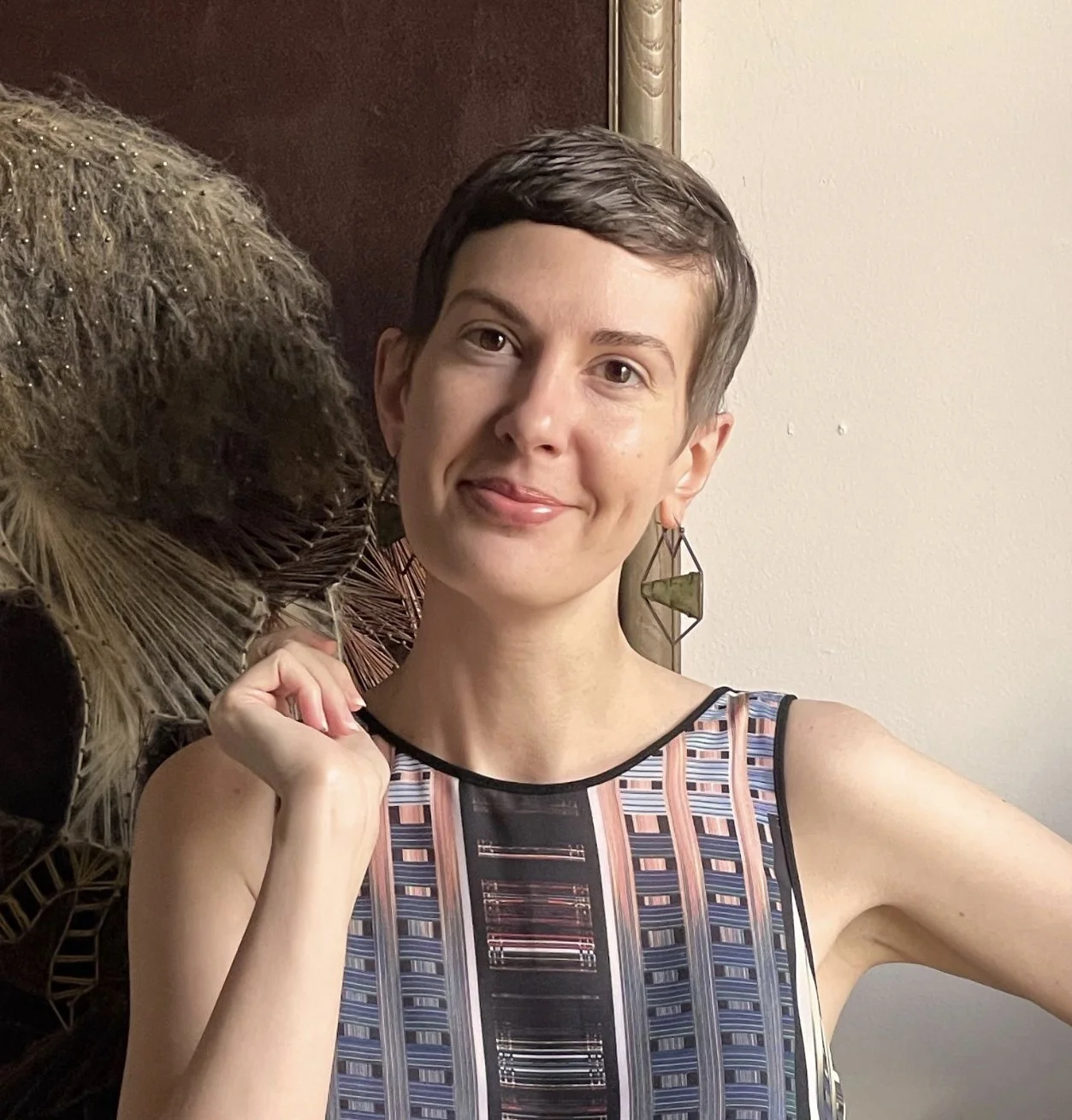 Patricia Lockwood standing in front of an embroidered owl canvas.