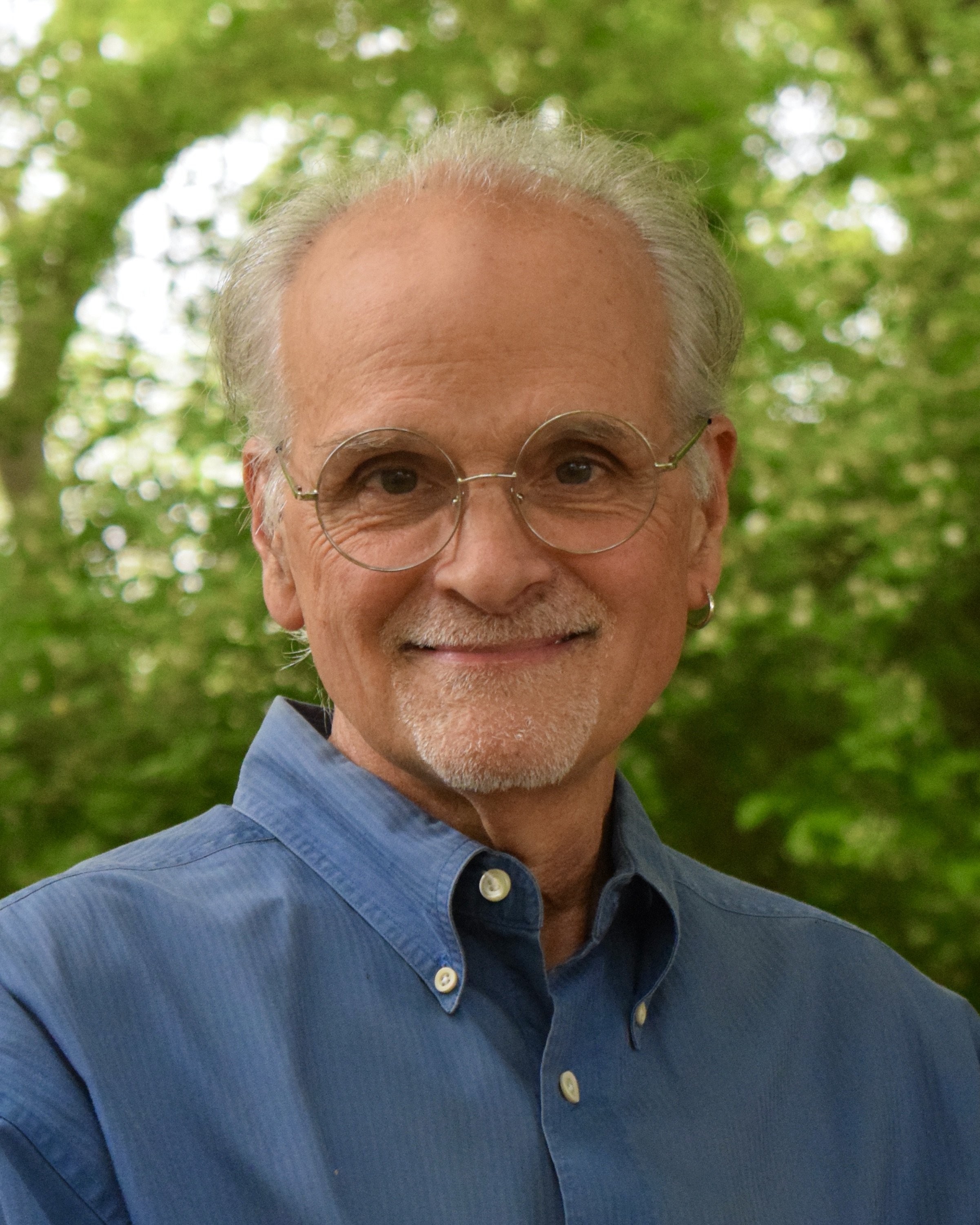 Jerry Gentry standing in front of green trees.