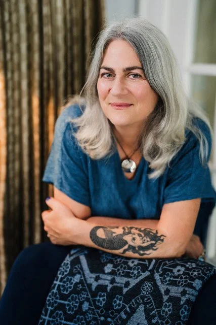 Laura Dickerman leaning on a navy blue chair.