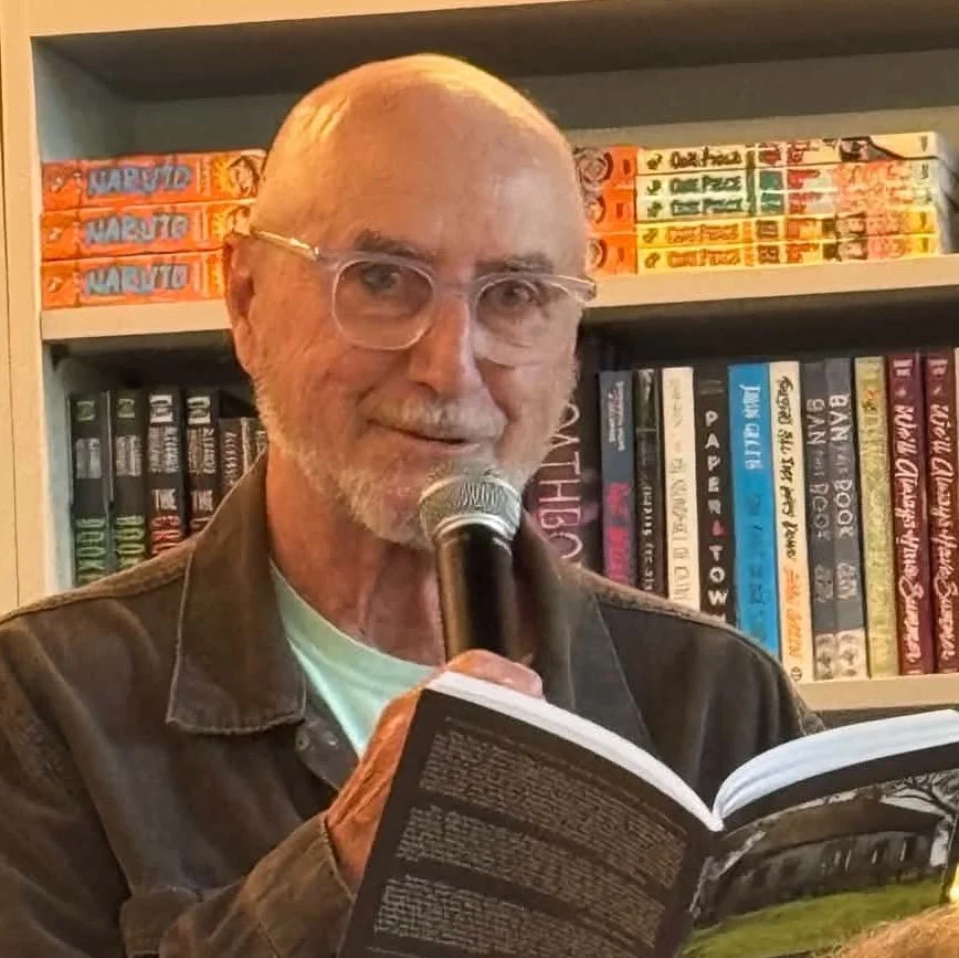 Rupert Fike holding a book and speaking into a microphone.