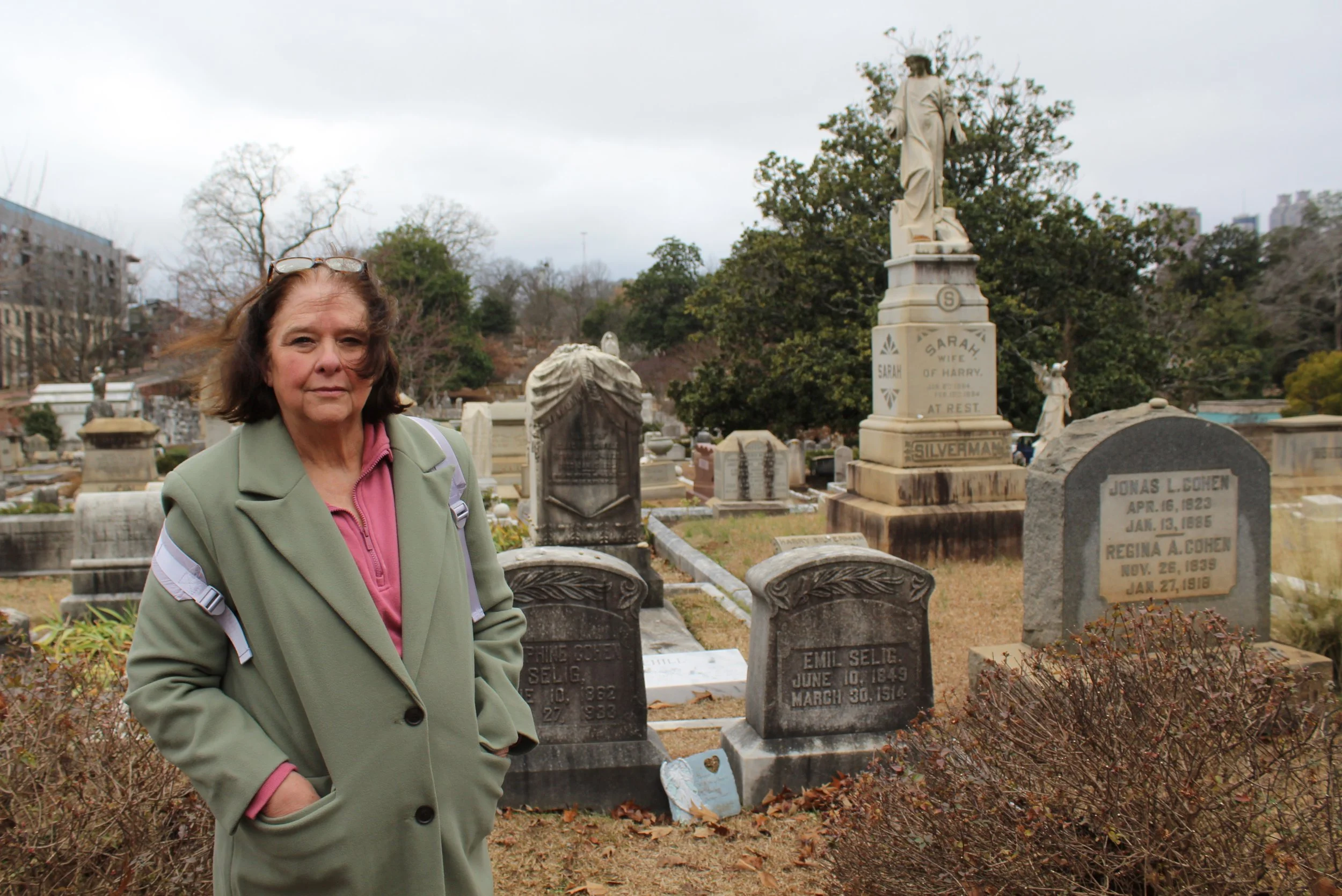 Ann Hite standing in front of dark gray tombstones.