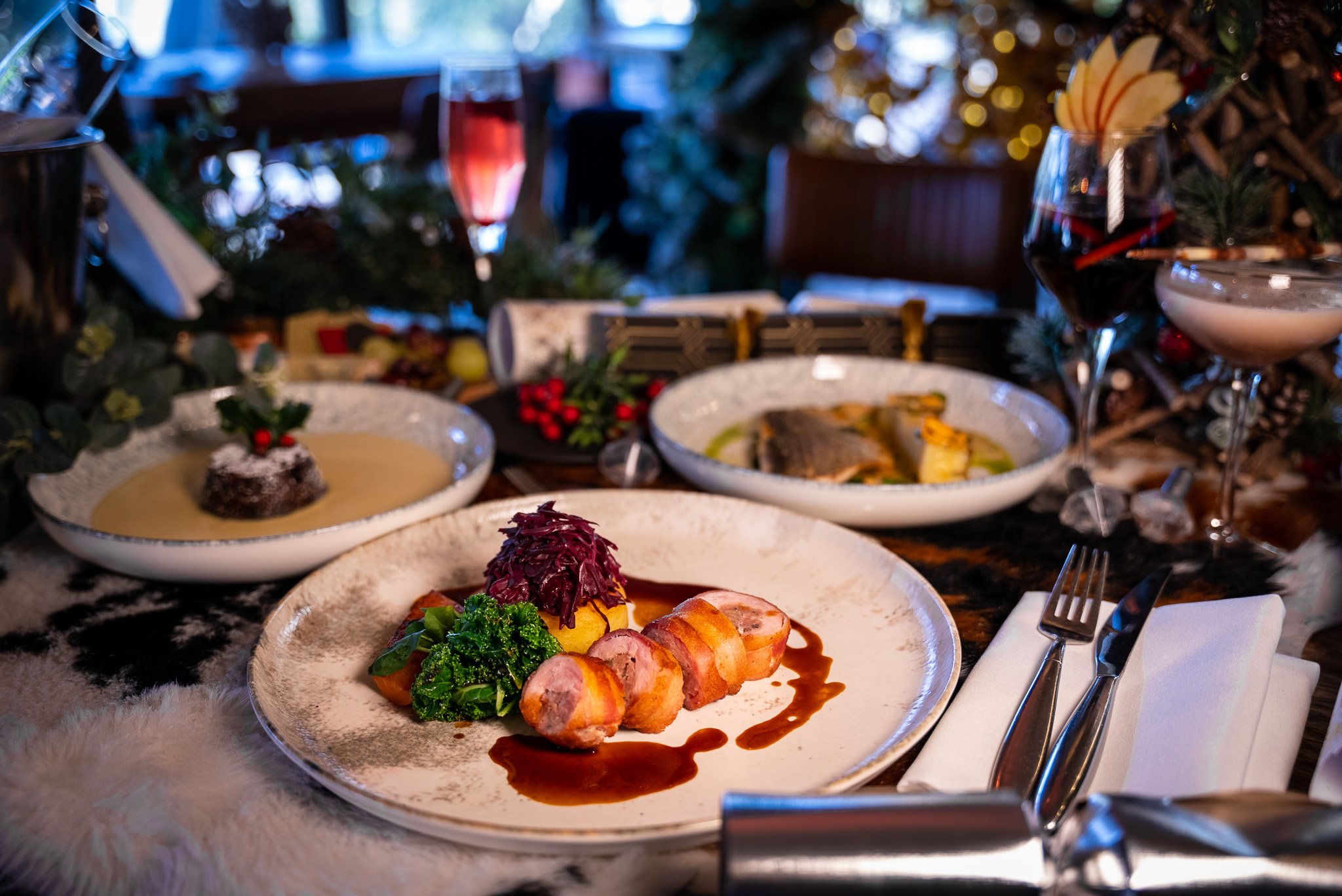 Festive table setting with plated gourmet dishes, wine glasses, and holiday decor.