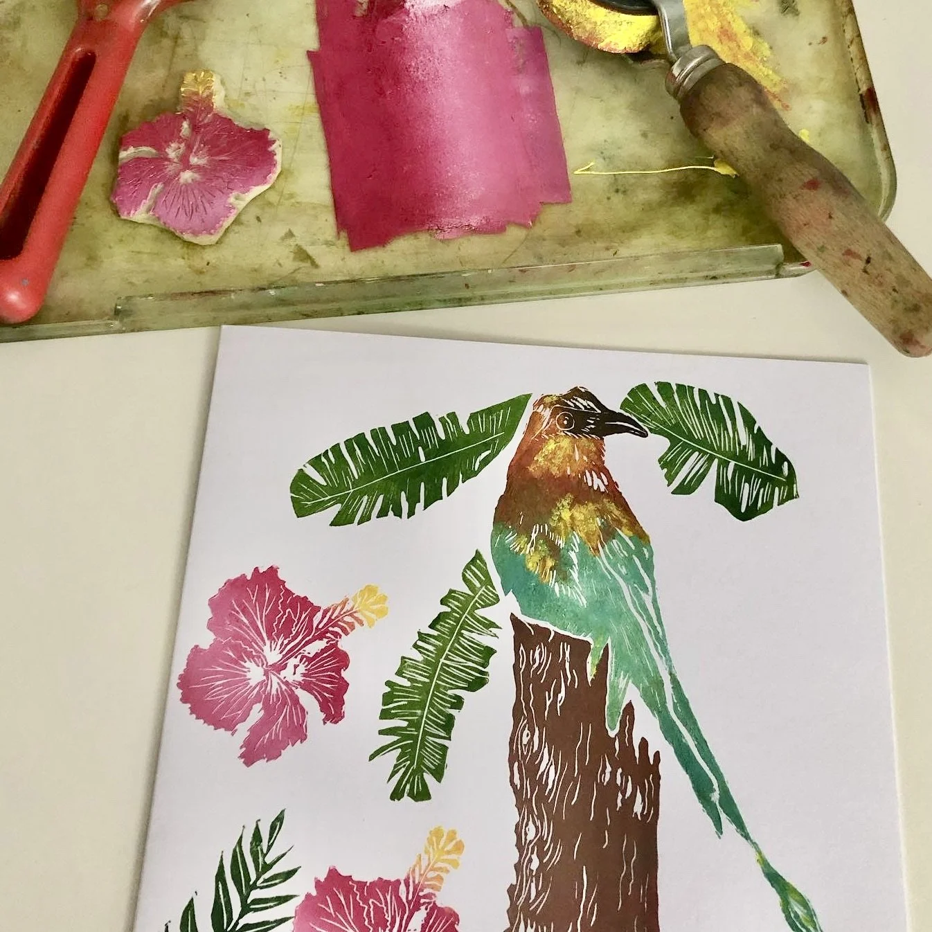 A colorful print of a bird perched on a tree branch, surrounded by green leaves and pink and yellow flowers.