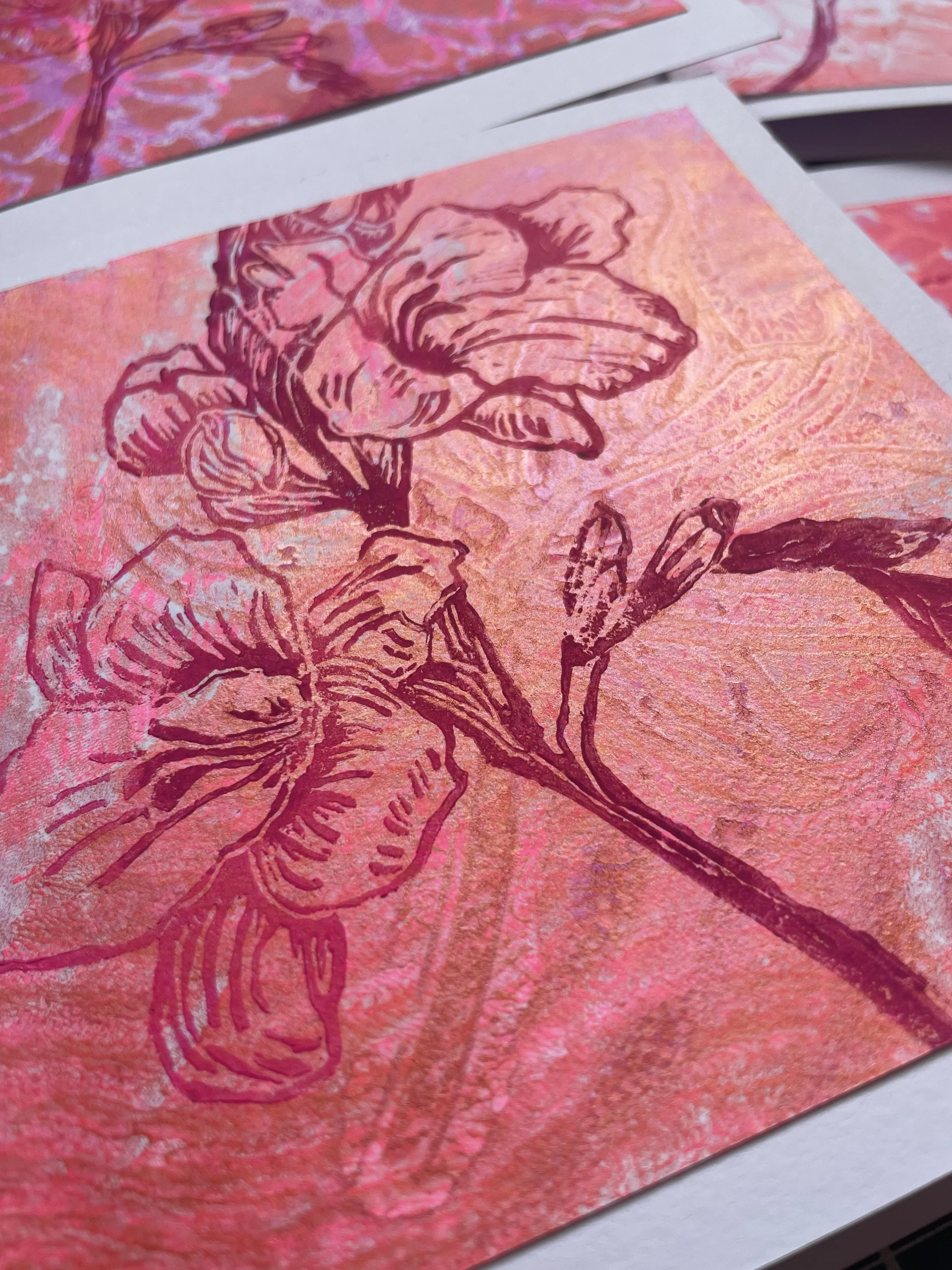 A close-up of a pink and orange art print featuring a line drawing of flower blossoms on textured paper.