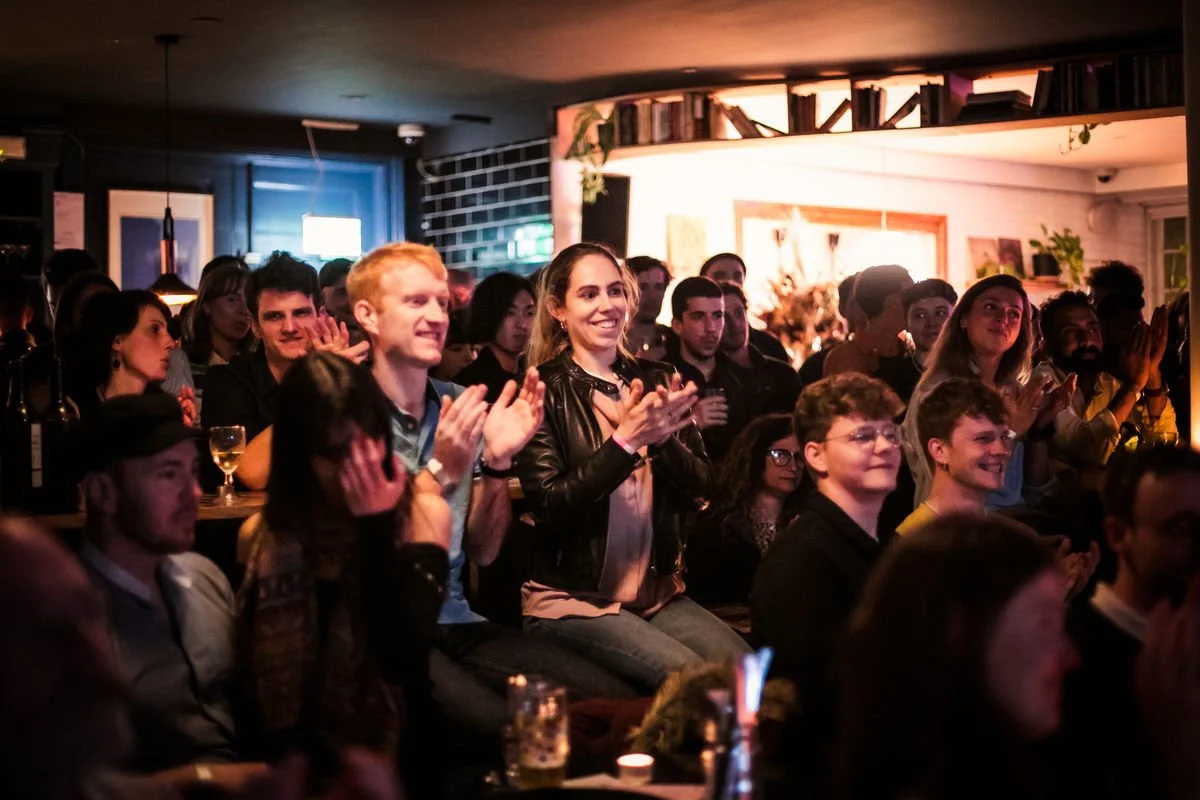 Group of people applauding in a dimly lit venue.
