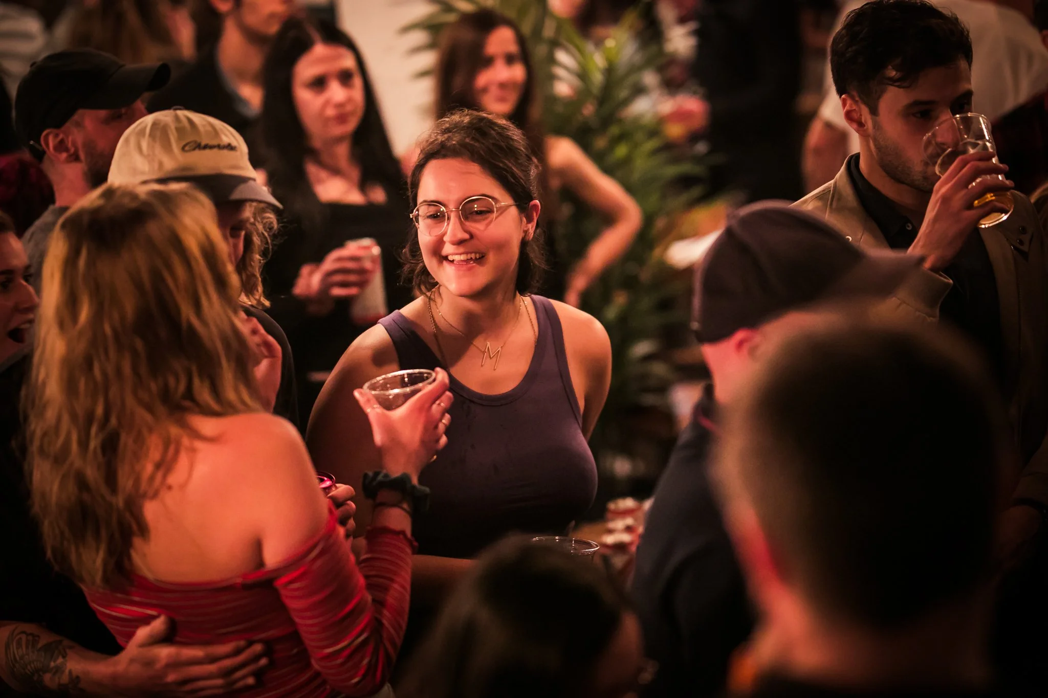 Group of people socializing at a party, holding drinks, and smiling.