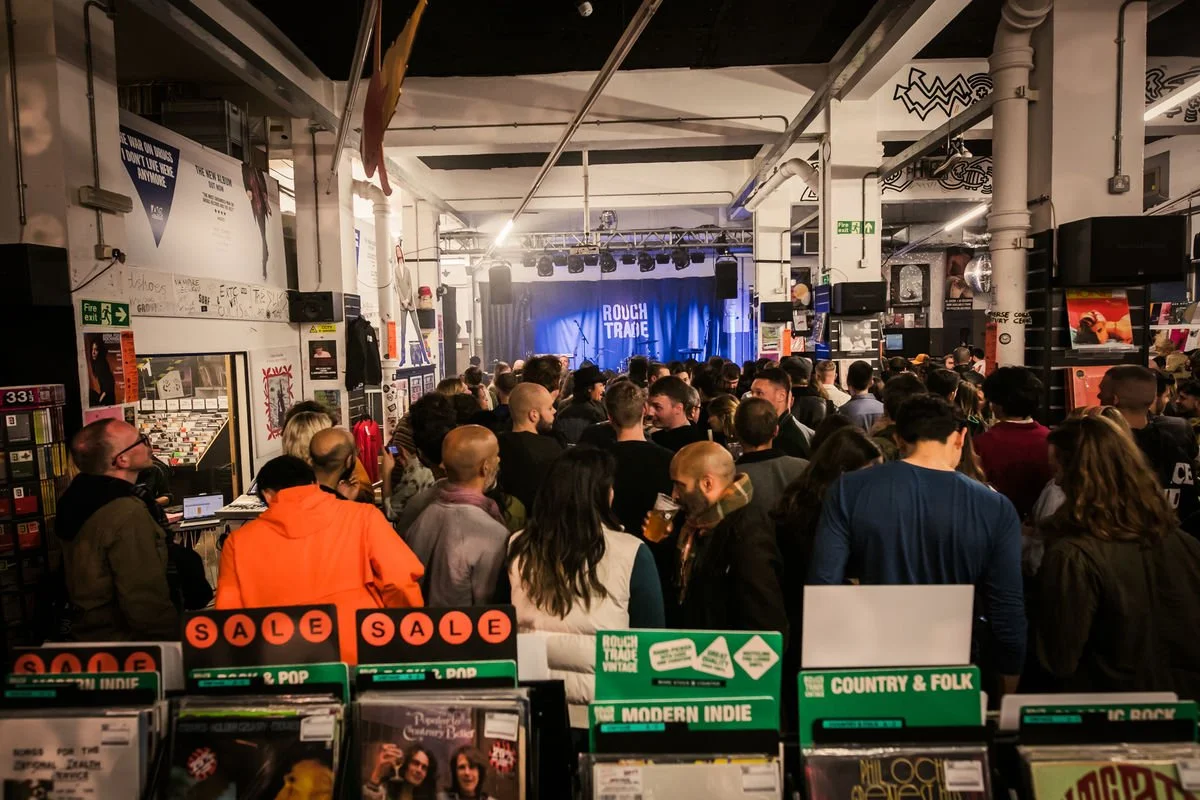 Crowd at music venue, Rough Trade, with vinyl records and stage.