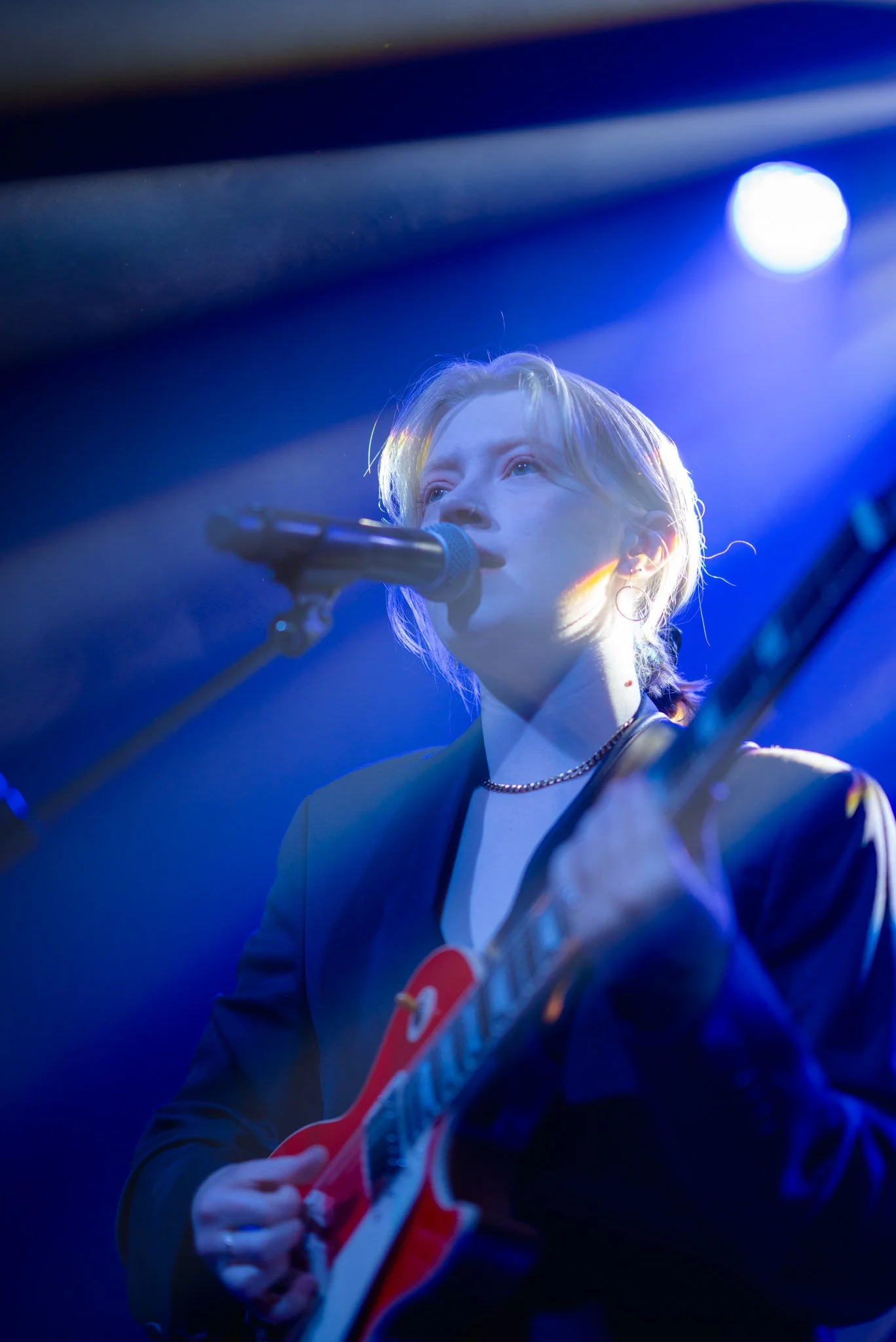 Person performing on stage with guitar under blue lighting