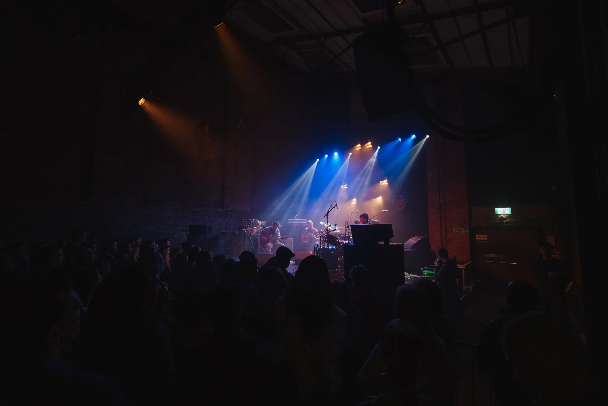 Live music concert with band performing on stage, colorful lighting