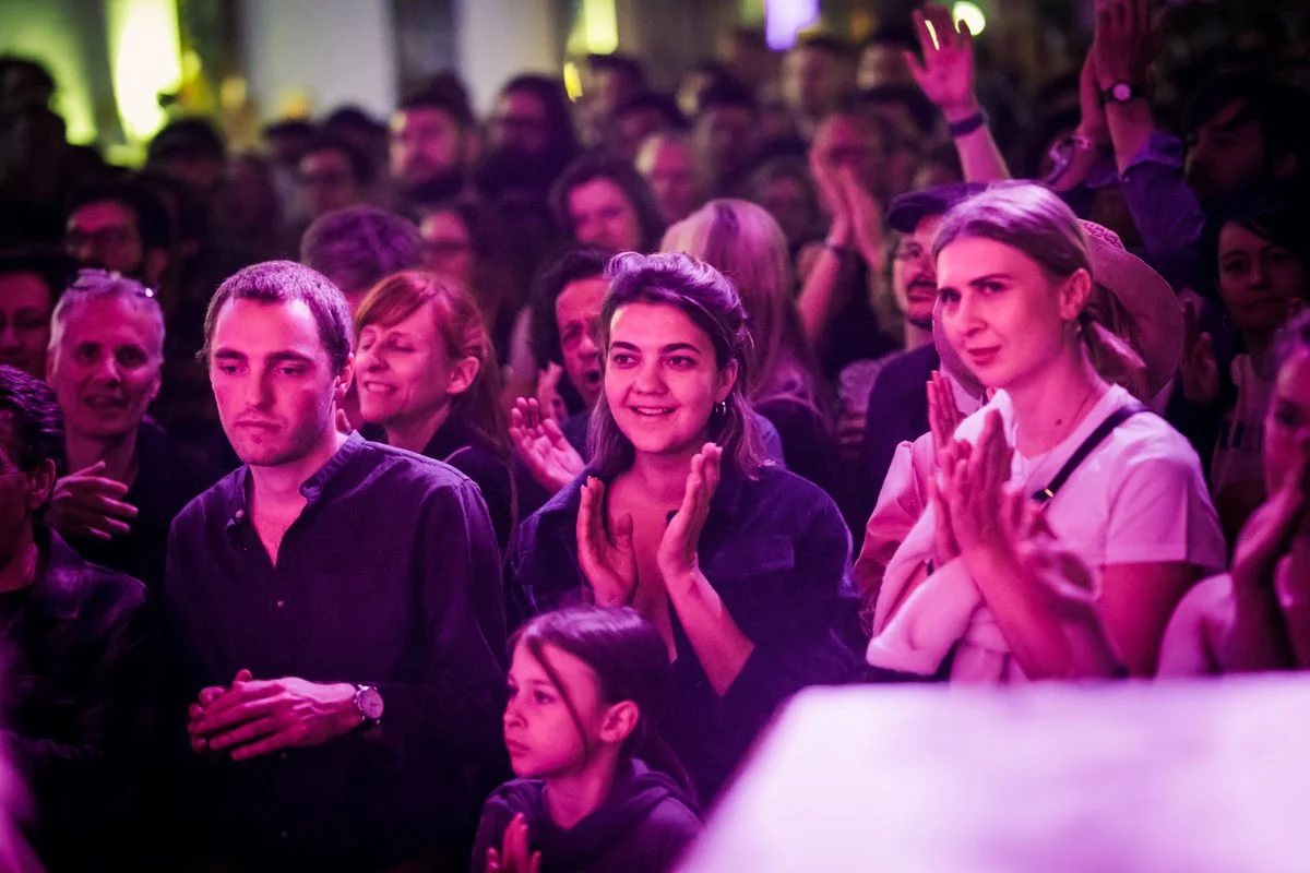 Audience clapping at event, purple lighting